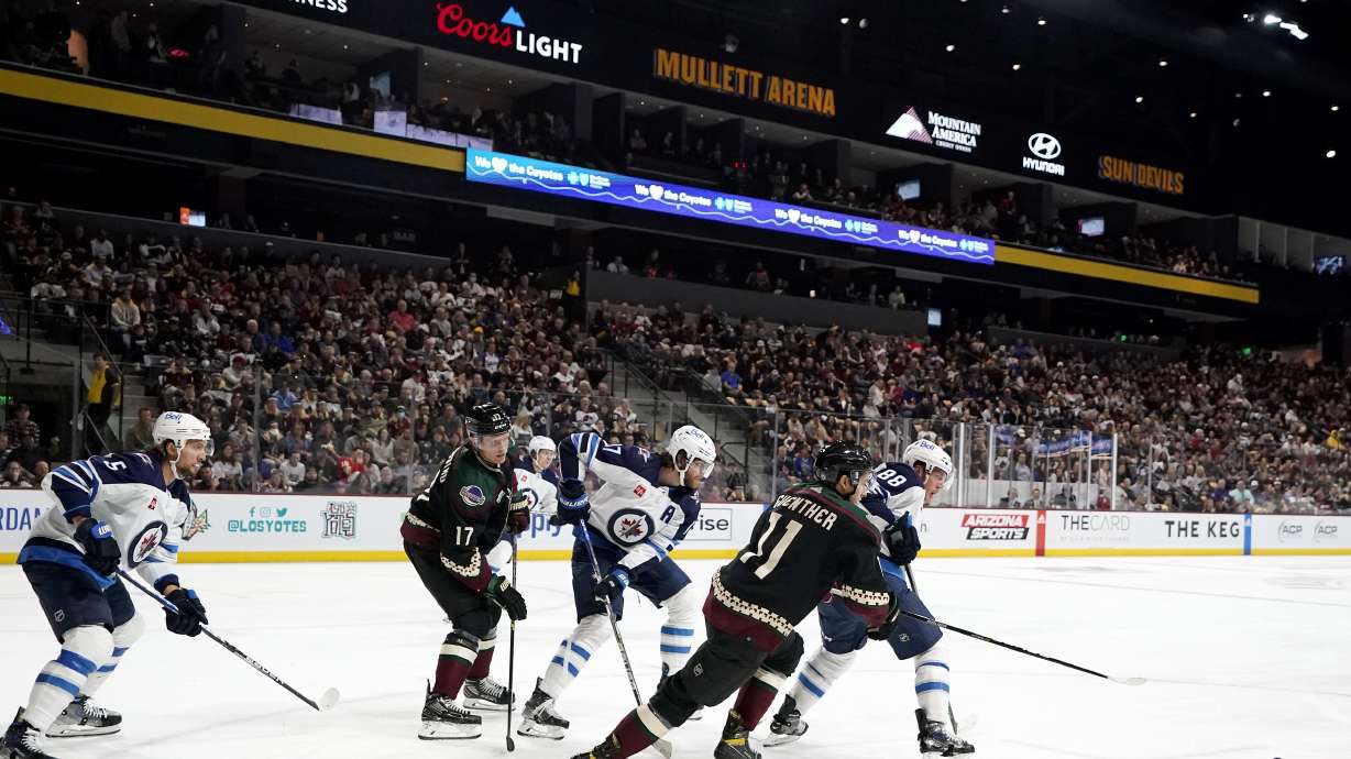 Winnipeg Jets defenseman Brenden Dillon (5), Arizona Coyotes center Nick Bjugstad (17), Jets center Adam Lowry (17), Coyotes right wing Dylan Guenther (11), and Jets defenseman Nate Schmidt (88) look for the puck during the first period of an NHL hockey game at Mullett Arena in Tempe, Ariz., Friday, Oct. 28, 2022.
