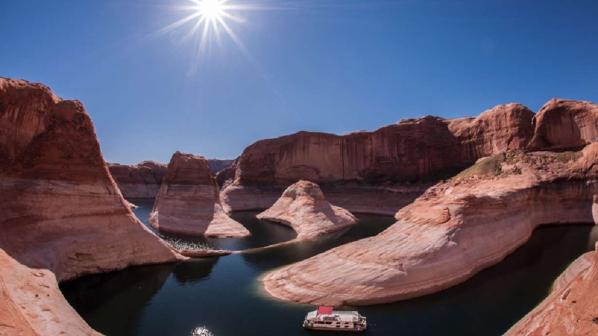 A houseboat sits in the green water and high orange cliffs of Lake Powell, Glen Canyon National Recreation Area, March 18, 2014. The Southern Utah Wilderness Alliance and the National Parks Conservation Association reached a settlement in their lawsuits against the National Park Service concerning off-road vehicle management at Glen Canyon National Recreation Area.