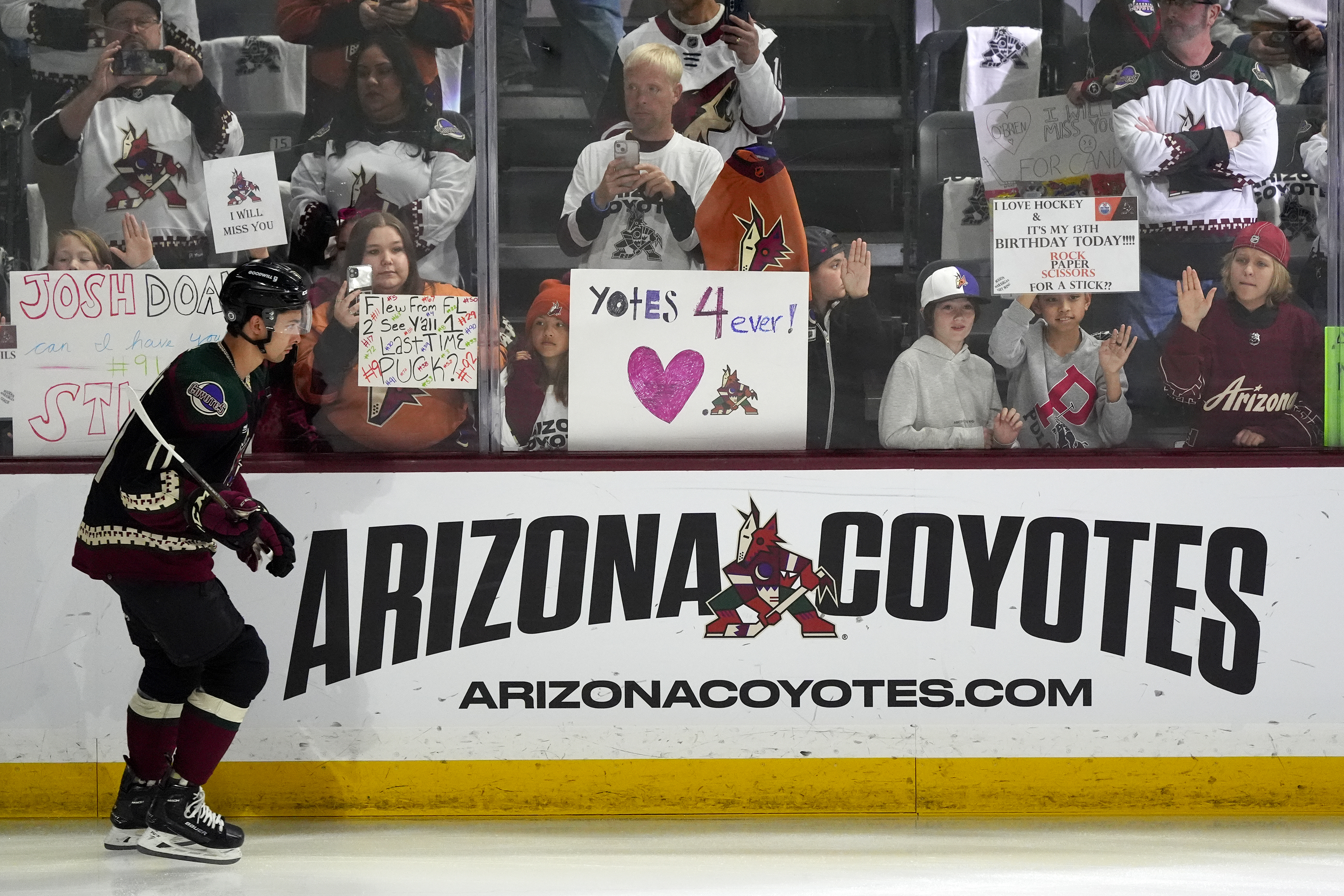 Arizona Coyotes' Dylan Guenther skates past fans as players warm up for an NHL hockey game against the Edmonton Oilers on Wednesday, April 17, 2024, in Tempe, Ariz. The Coyotes are moving to Salt Lake City in a deal that could be signed less than 24 hours after the game. Hockey could return, perhaps within five years, but the stark reality is this is the end for the foreseeable future.