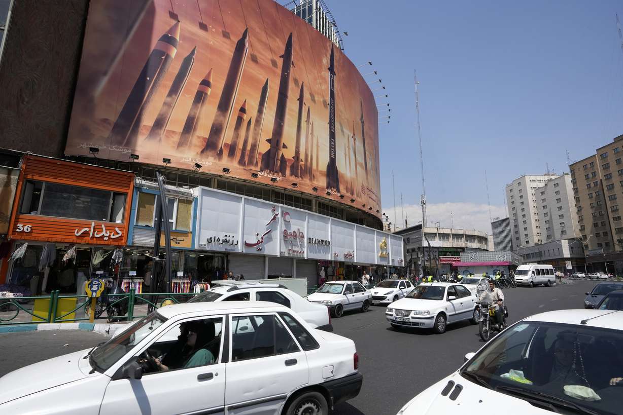 Vehicles drive past an anti-Israeli banner showing missiles being launched, in a square in downtown Tehran, Iran, Friday.