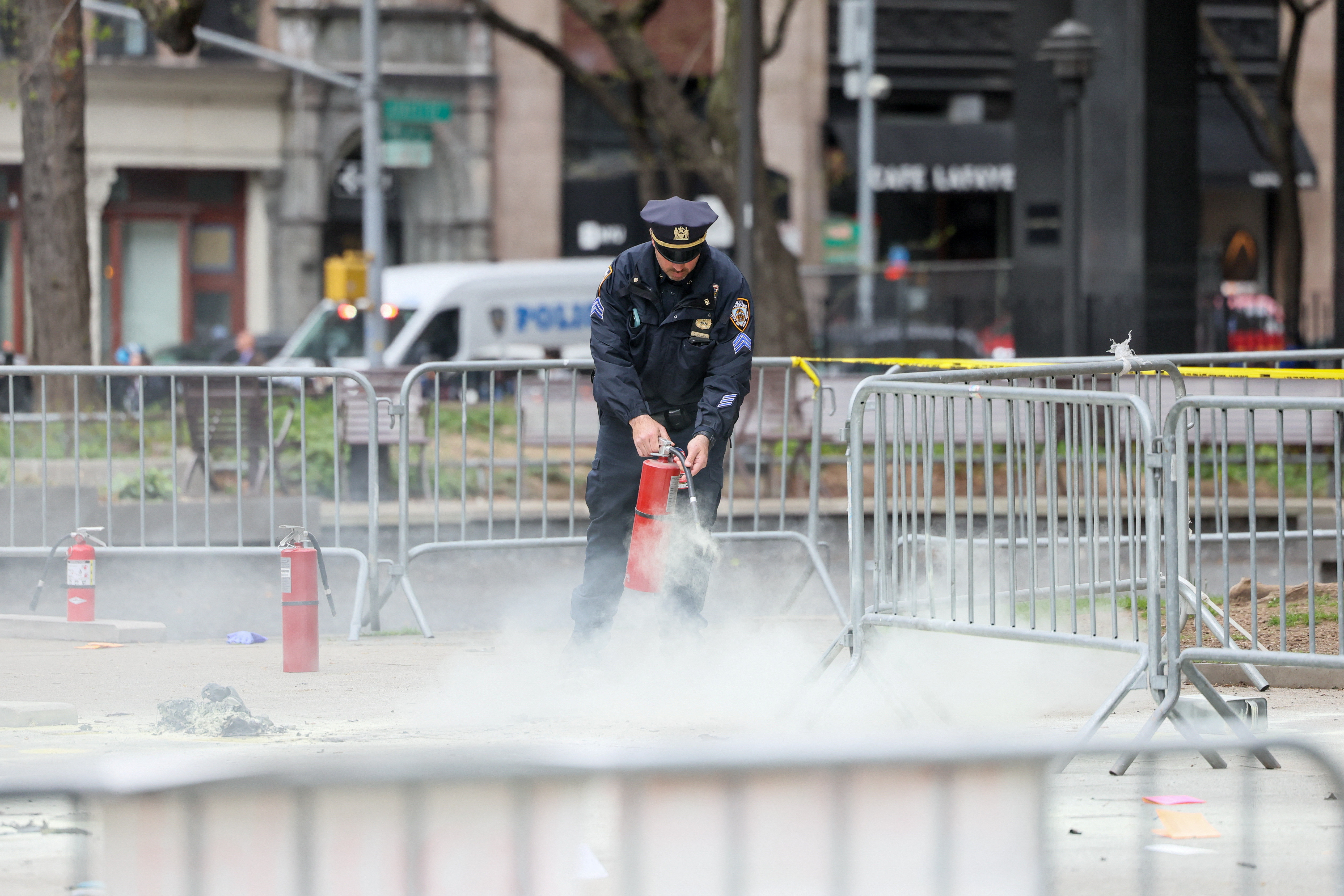 A police officer uses a fire extinguisher as emergency personnel respond to a report of a person covered in flames, outside the courthouse where former U.S. President Donald Trump's criminal hush money trial is underway, in New York, April 19, 2024.