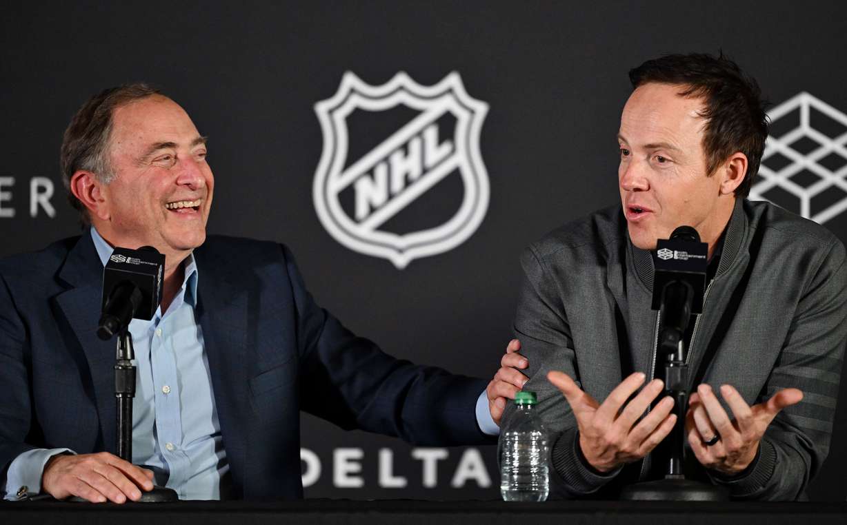 NHL Commissioner Gary Bettman laughs as Ryan Smith, co-founder and chairman of Smith Entertainment Group, speaks at a press conference at the Delta Center in Salt Lake City to announce that the NHL would be coming to Utah on Friday.