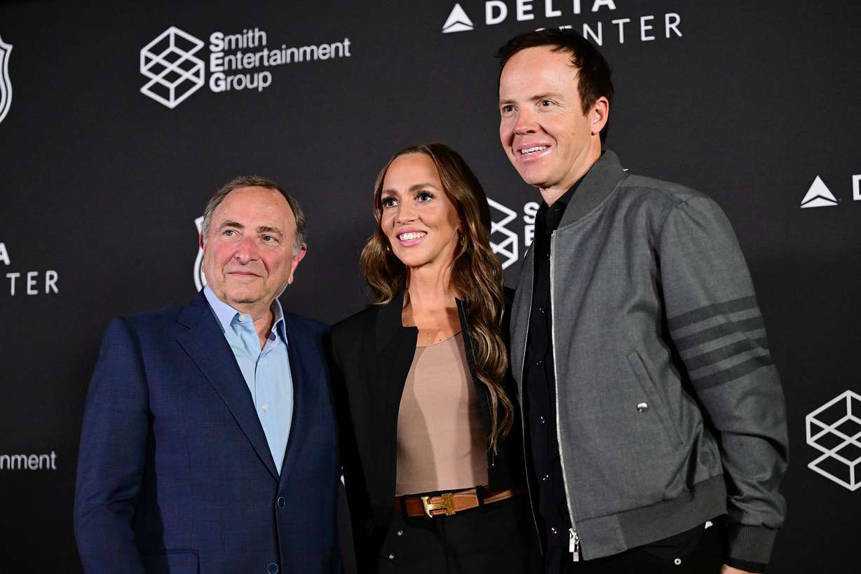 Ryan Smith, co-founder and chairman of Smith Entertainment Group, and Ashley Smith, co-founder of Smith Entertainment Group, pose with NHL Commissioner Gary Bettman after their press conference at the Delta Center in Salt Lake City to announce that the NHL would be coming to Utah on Friday.