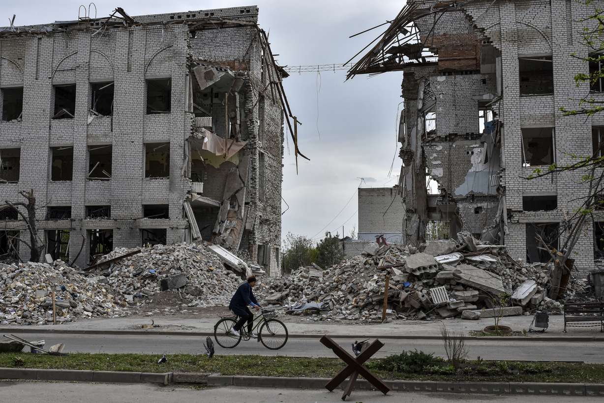 A local woman rides a bicycle on Thursday in front of a building destroyed by a Russian airstrike in the frontline town of Orikhiv, Ukraine. House Speaker Mike Johnson, R-La., putting his job on the line, relied on Democratic support this week to bring to the House floor a series of votes on $95 billion in foreign aid for Ukraine, Israel and other U.S. allies.