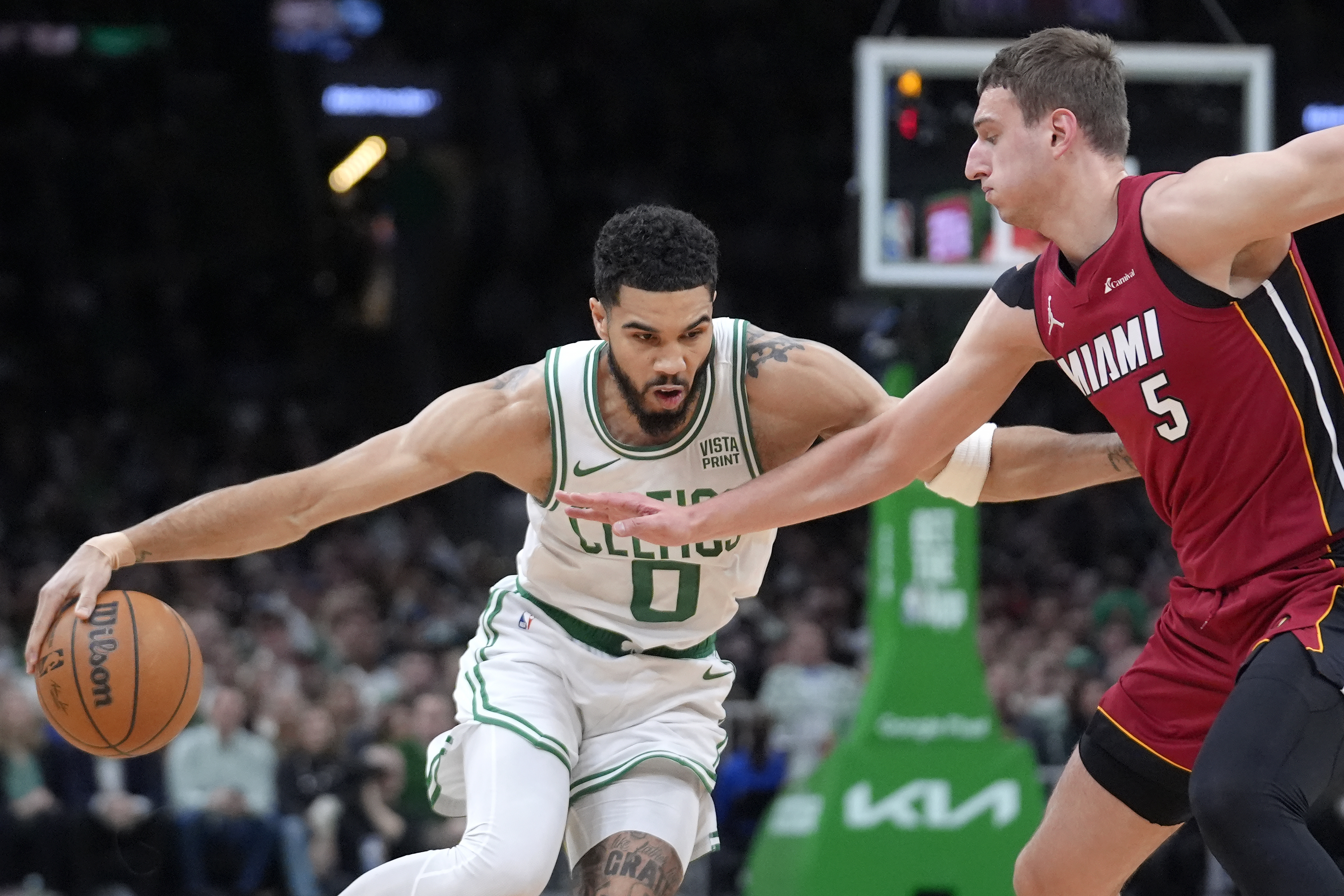 Boston Celtics forward Jayson Tatum (0) drives past Miami Heat forward Nikola Jovic (5) in the first half of Game 1 of an NBA basketball first-round playoff series, Sunday, April 21, 2024, in Boston. 
