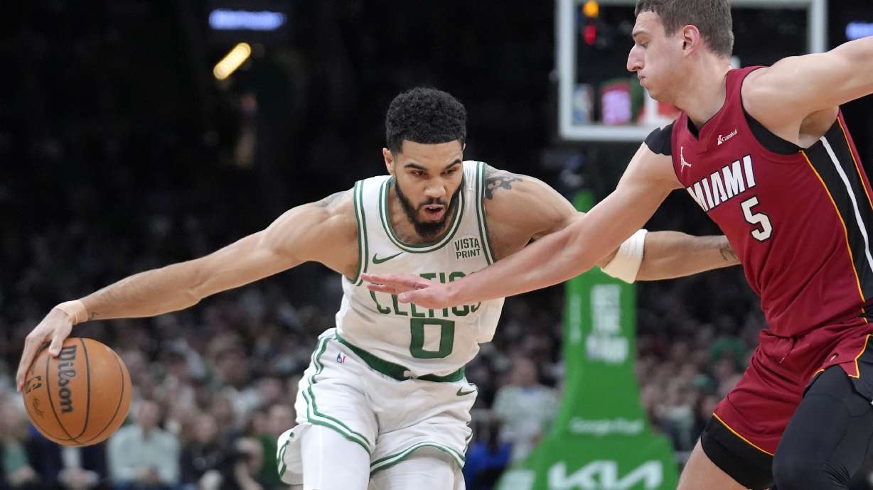 Boston Celtics forward Jayson Tatum (0) drives past Miami Heat forward Nikola Jovic (5) in the first half of Game 1 of an NBA basketball first-round playoff series, Sunday, April 21, 2024, in Boston.
