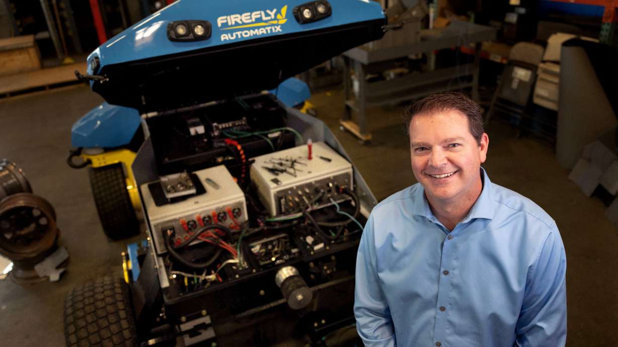 Matt Aposhian, president and COO of FireFly Automatix, stands beside a fully autonomous lawn mower at FireFly Automatix in Salt Lake City on March 13.