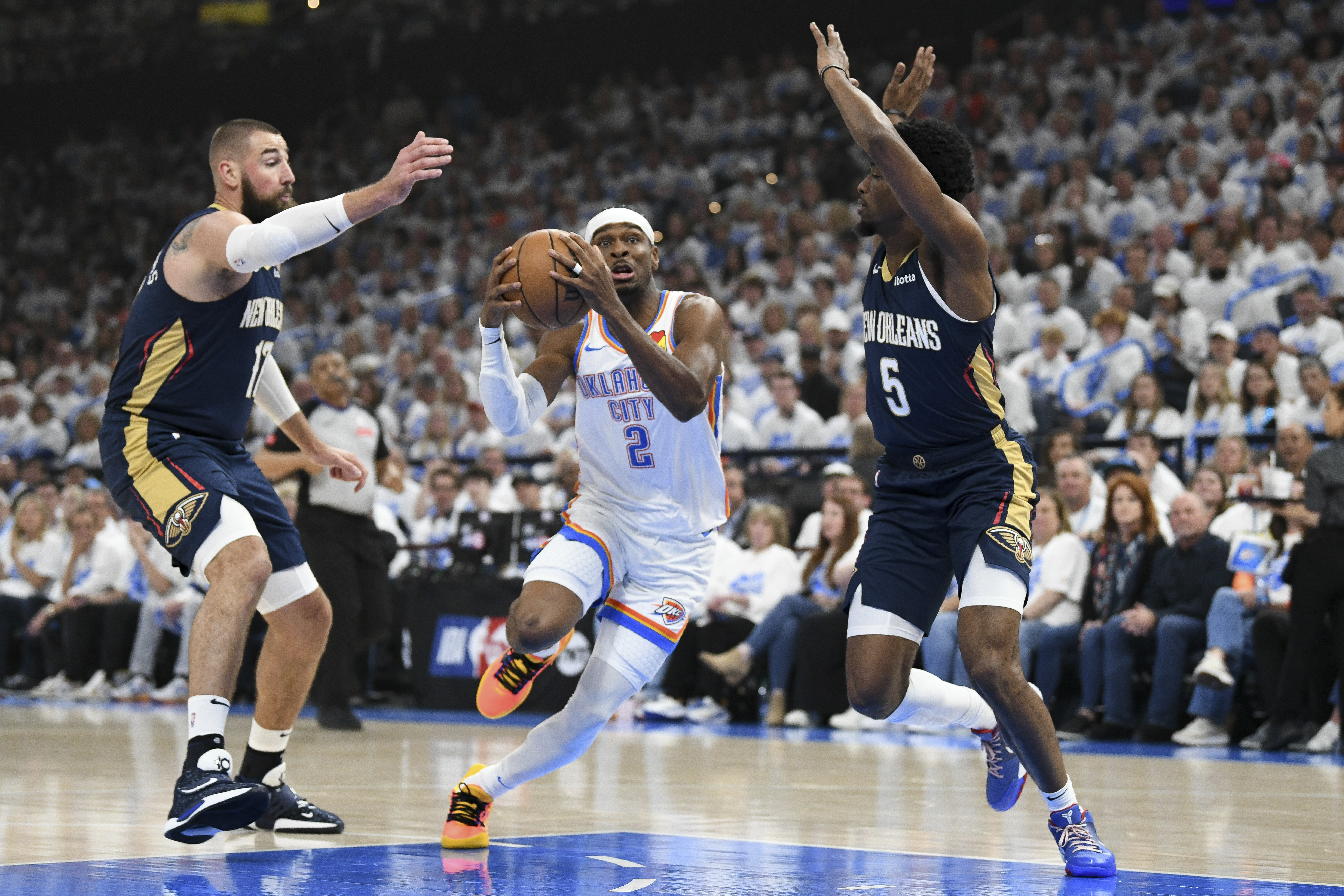 Oklahoma City Thunder guard Shai Gilgeous-Alexander (2) drives past New Orleans Pelicans center Jonas Valanciunas, left, and forward Herbert Jones (5) in the first half of Game 1 of an NBA basketball first-round playoff series, Sunday, April 21, 2024, in Oklahoma City.