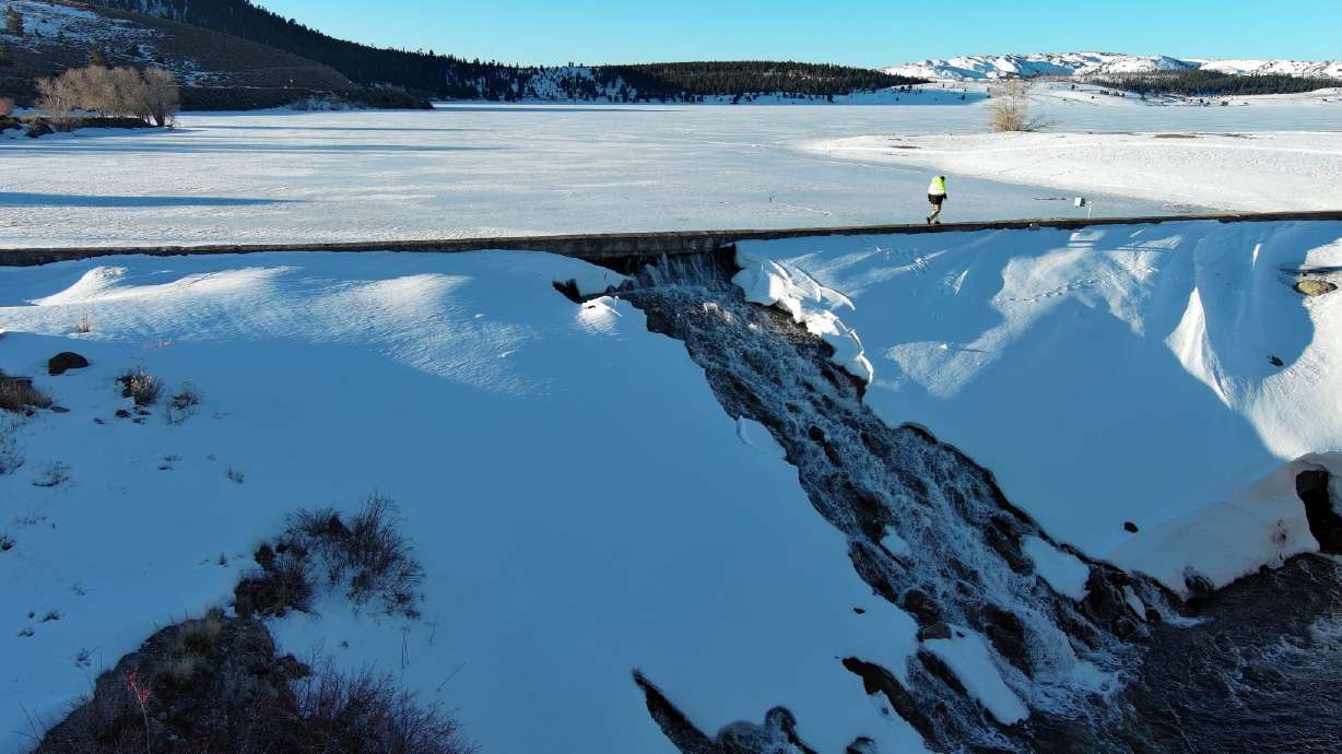 A construction worker walks across the Panguitch Lake dam on April 10 to assess damage to it. The Utah Division of Wildlife Resources reopened the reservoir to fishing on Monday.