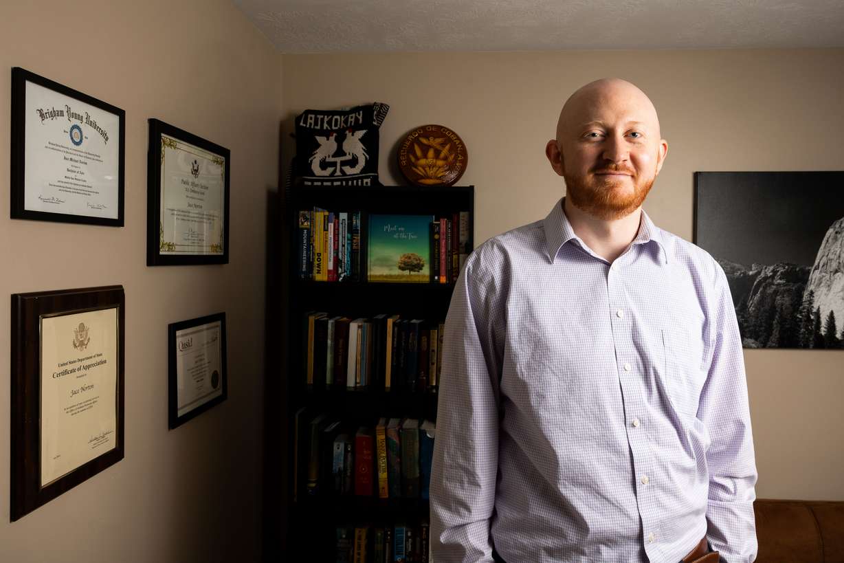 Jace Norton, founder and CEO of Maya Bridge Language Services, poses for a portrait in his home office in South Jordan, April 10. The bookshelf behind him holds books in multiple different languages and items he got in Guatemala while serving a mission for The Church of Jesus Christ of Latter-day Saints.