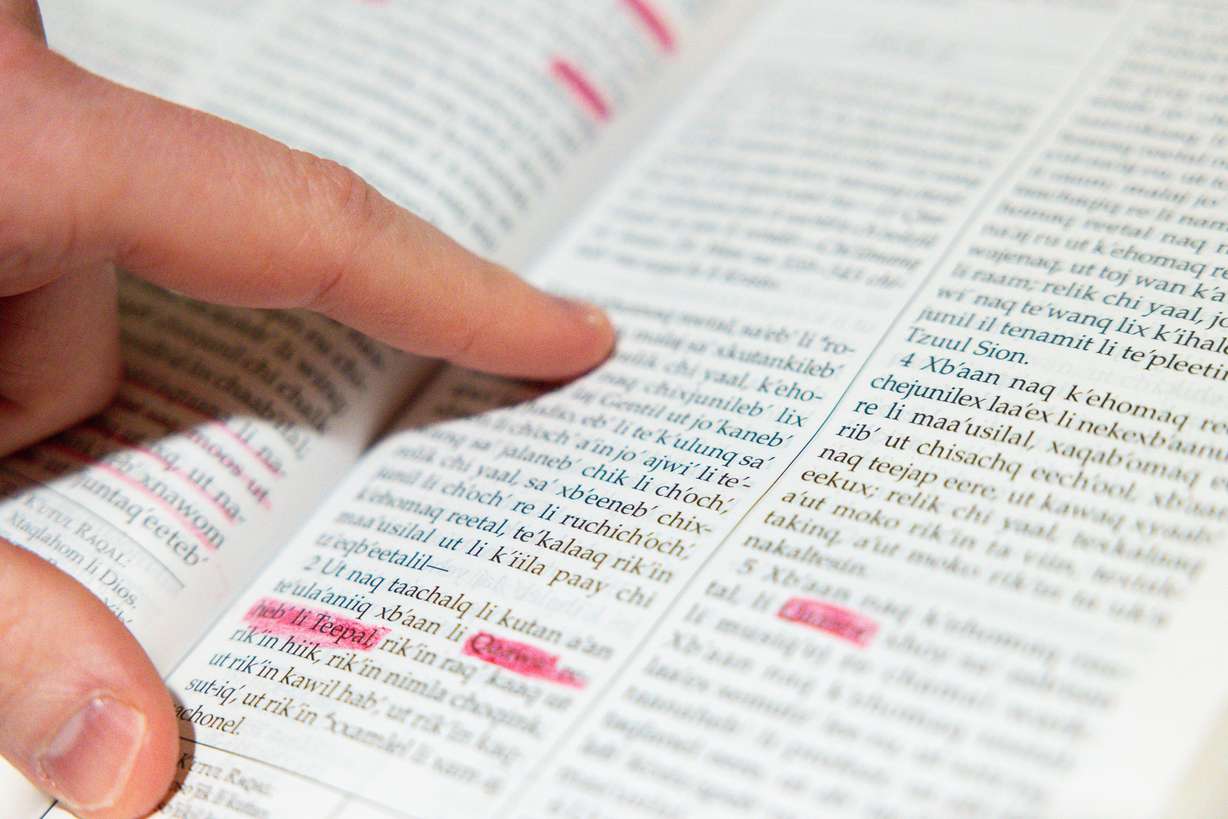Jace Norton, founder and CEO of Maya Bridge Language Services, points out characters in a Q'eqchi' Book of Mormon in his home office in South Jordan, April 10.