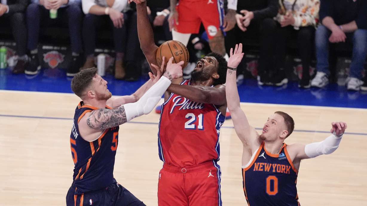 New York Knicks' Isaiah Hartenstein, left, and Donte DiVincenzo, right, defend against Philadelphia 76ers' Joel Embiid (21) during the second half of Game 2 in an NBA basketball first-round playoff series Monday, April 22, 2024, in New York.