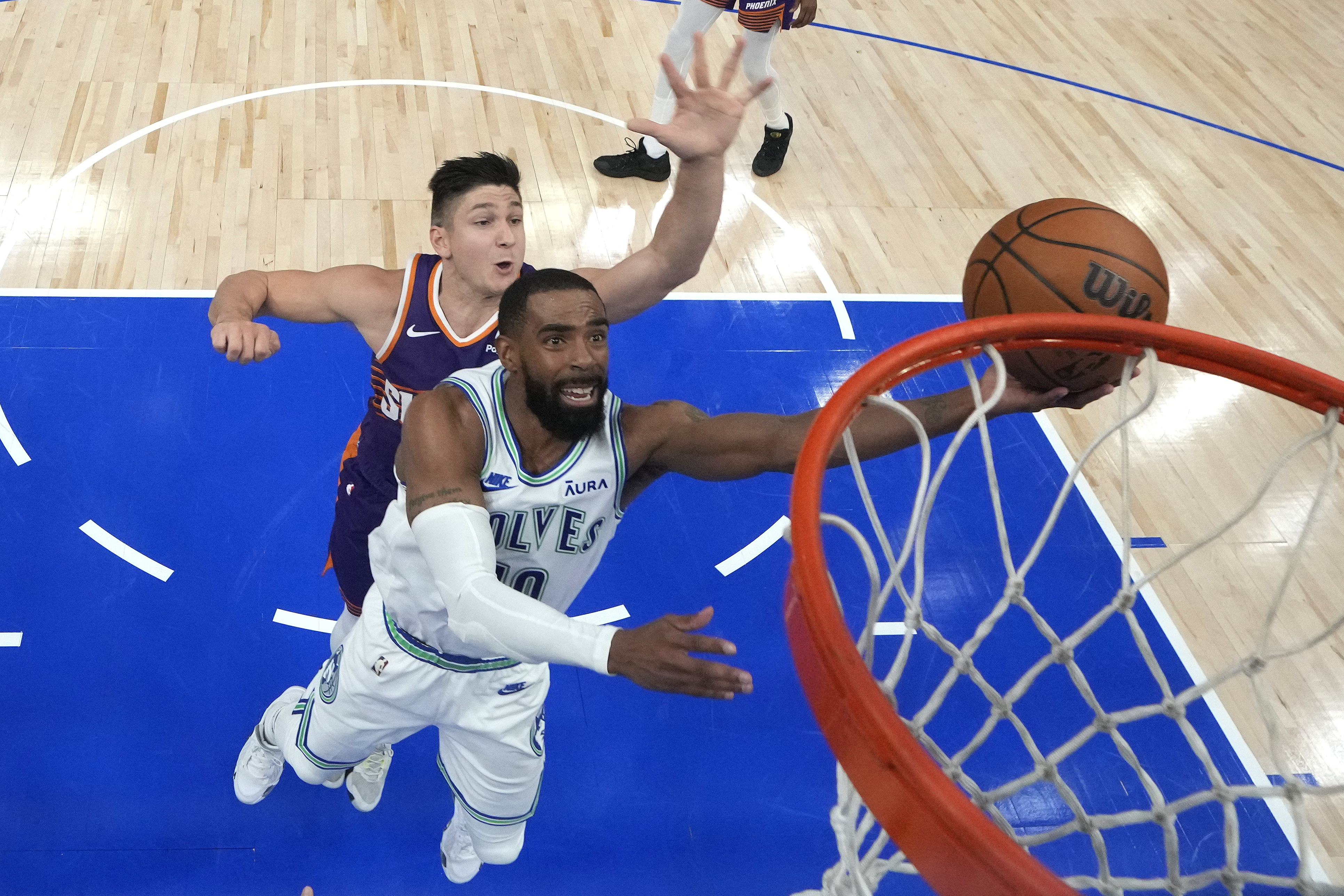 Minnesota Timberwolves guard Mike Conley, front, shoots as Phoenix Suns guard Grayson Allen defends during the second half of Game 2 of an NBA basketball first-round playoff series Tuesday, April 23, 2024, in Minneapolis.