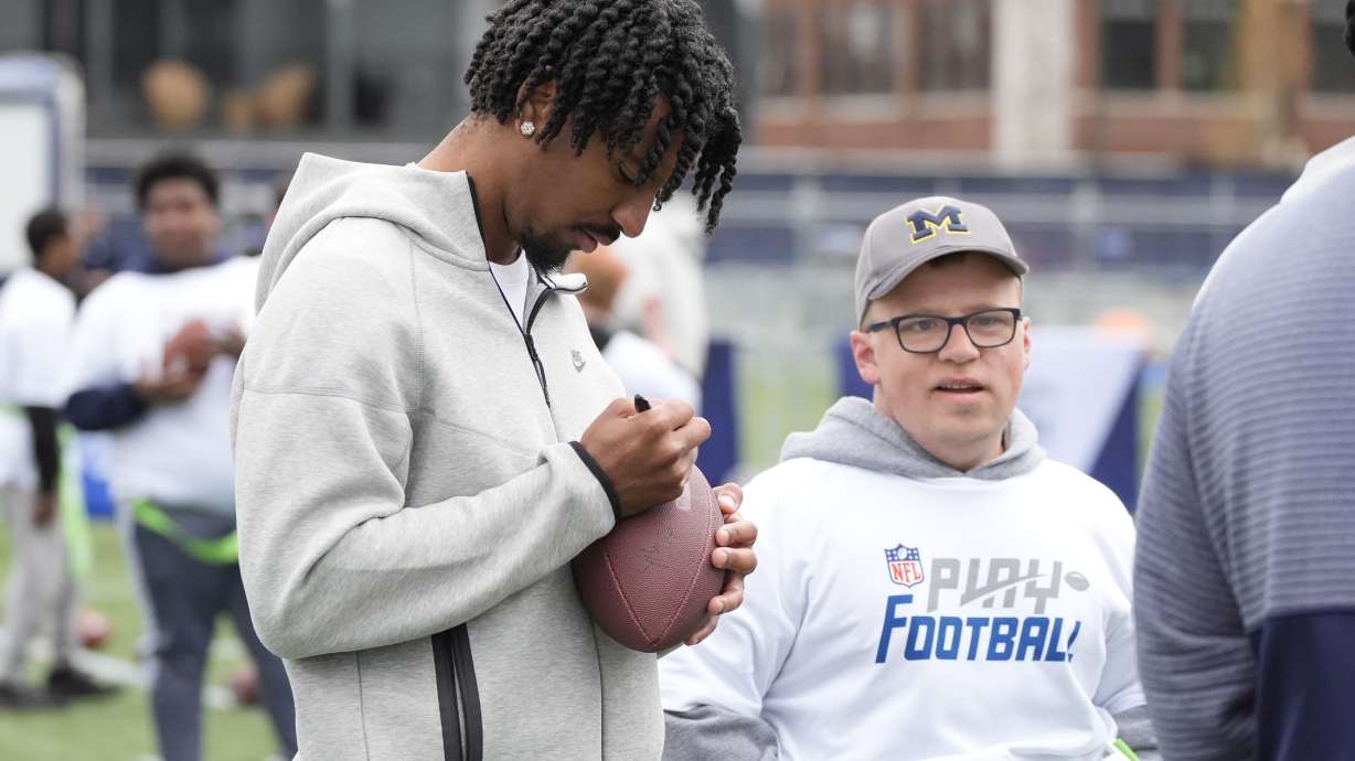 LSU quarterback Jayden Daniels signs a football for a young athlete during an NFL Football Play Football Prospect Clinic with Special Olympics athletes, Wednesday, April 24, 2024 in Detroit.