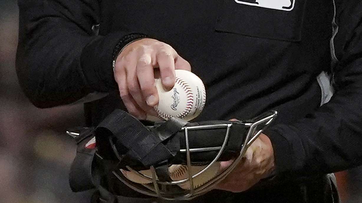FILE - An umpire puts a ball into his face mask during a Major League Baseball game in San Francisco, Tuesday, June 15, 2021. A fired minor league umpire sued Major League Baseball, Wednesday, April 24, 2024, claiming he was sexually harassed by a female umpire and discriminated against because he is male and bisexual.