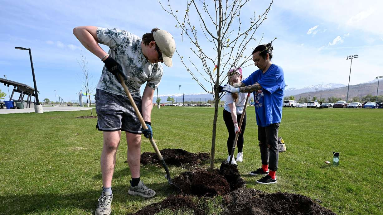 Jaxon Mercer, Rachel Starr and Alonso Prieto plant a tree as they join with Salt Lake City Department of Public Lands for an Earth Day and Arbor Day celebration to plant more than 250 trees at the Regional Athletic Complex in Rose Park on Monday.