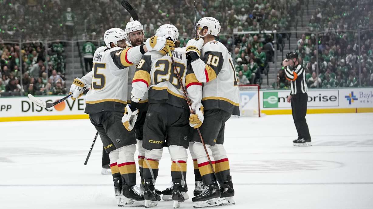 Vegas Golden Knights players surround Noah Hanifin after he scored against the Dallas Stars during the second period in Game 2 of an NHL hockey Stanley Cup first-round playoff series in Dallas, Wednesday, April 24, 2024.