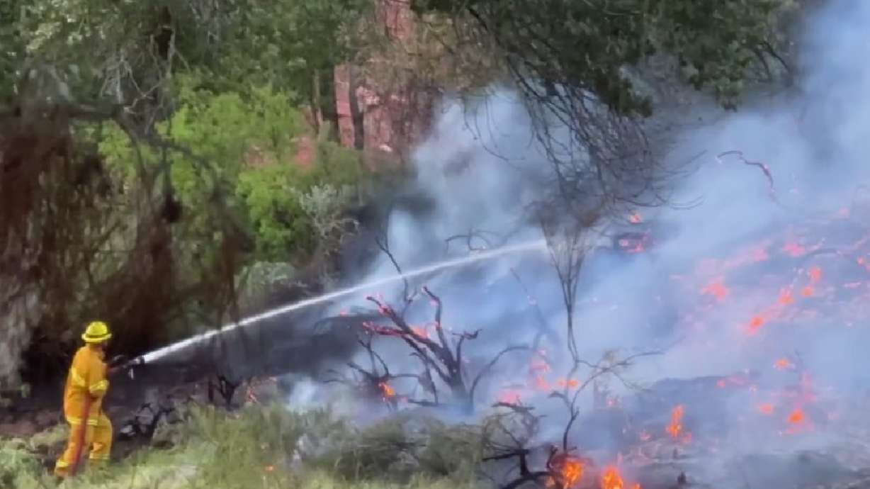 A firefighter douses the flames at Brooks Nature Park in St. George on Wednesday.