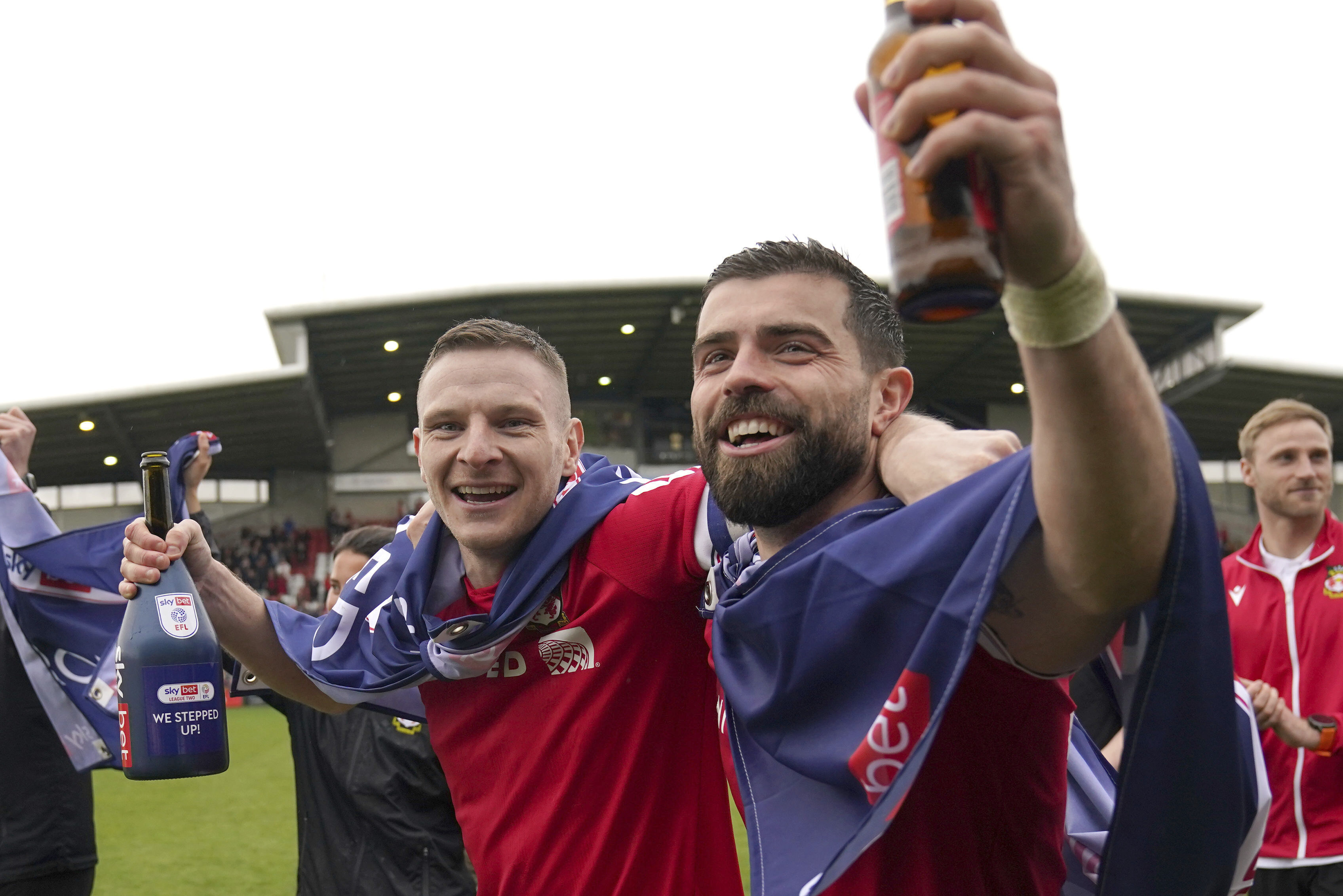 Wrexham's Paul Mullin and Elliot Lee on the pitch celebrating promotion to League One after the final whistle of the Sky Bet League Two match at the SToK Cae Ras, Wrexham, Saturday April 13, 2024.