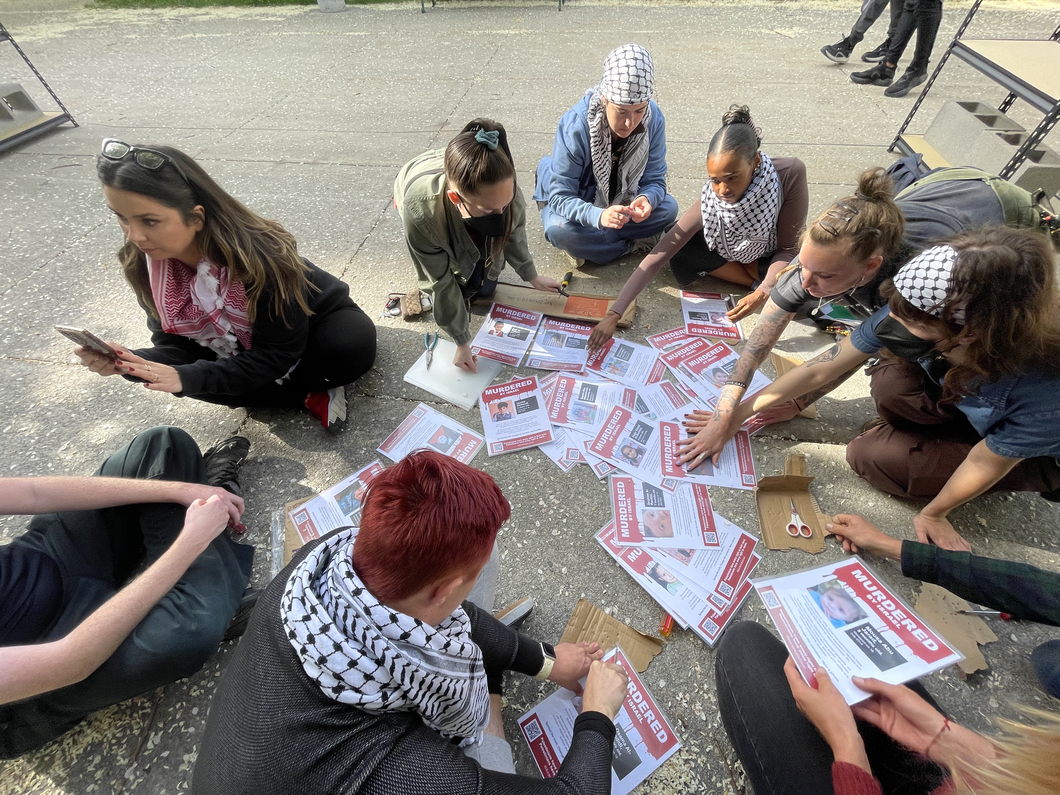 The contingent helps Thursday with installation of a memorial to Palestinians killed in the ongoing Israel-Hamas war in Gaza sorts through images of people purportedly killed at the hands of Israeli forces.