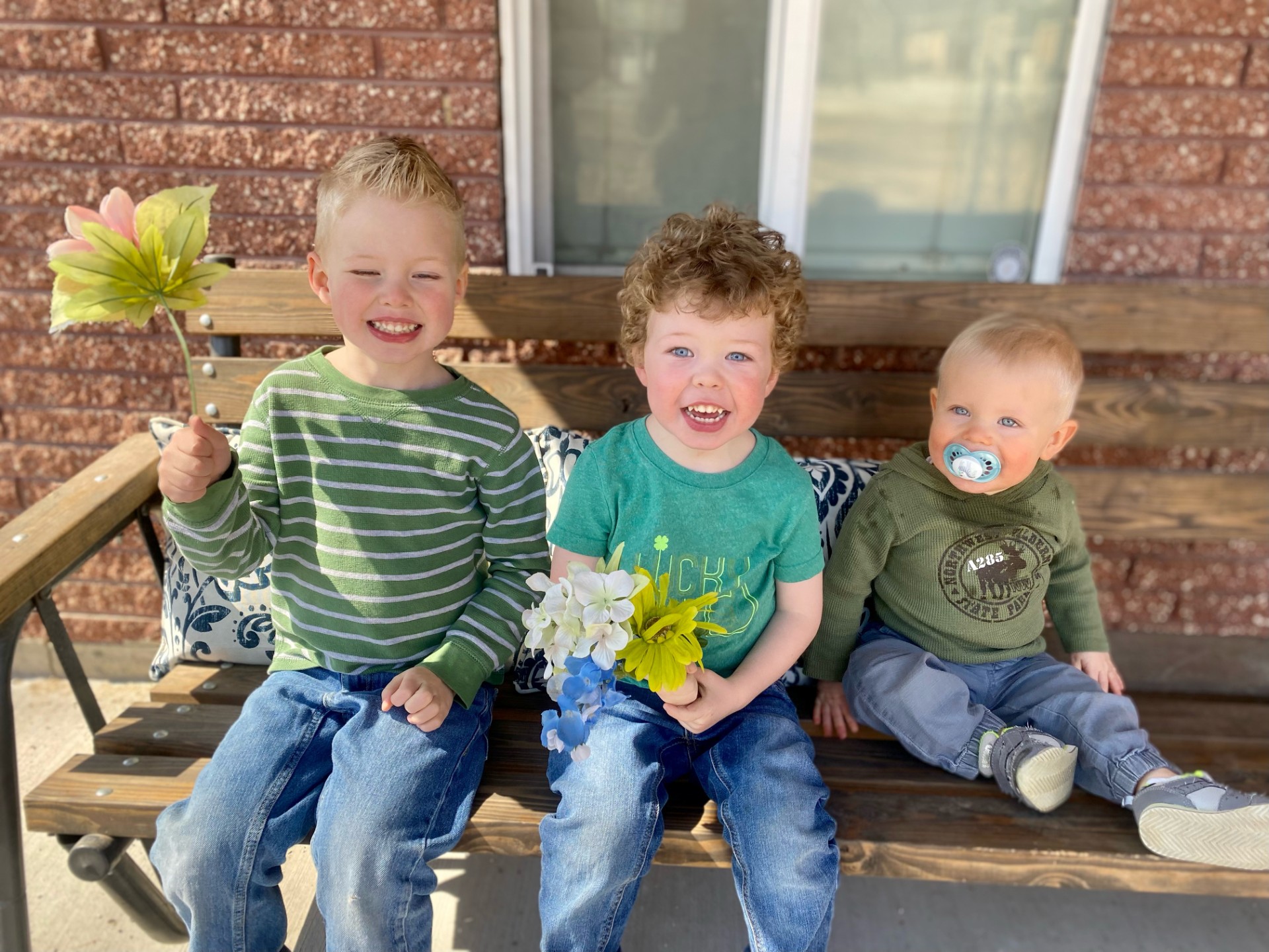 (From left to right) 7-year-old Liam, 5-year-old Ollie, and 3-year-old Milo, sitting on a bench together.