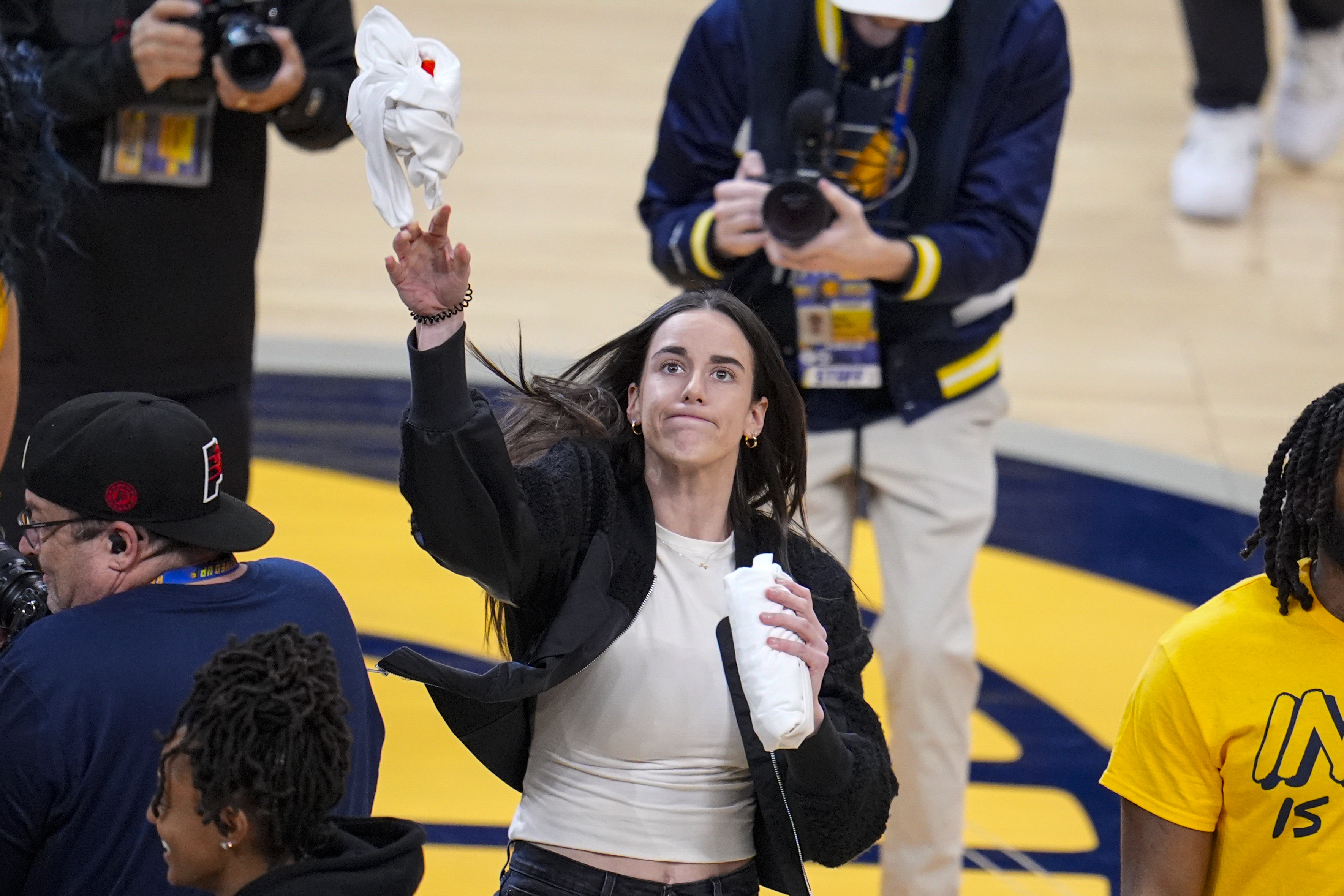 Indiana Fever player Caitlin Clark throws a tee-shirt to a fan during a time out during the first half between the Indiana Pacers and the Milwaukee Bucks in Game 2 in an NBA basketball first-round playoff series, Friday, April 26, 2024, in Indianapolis.