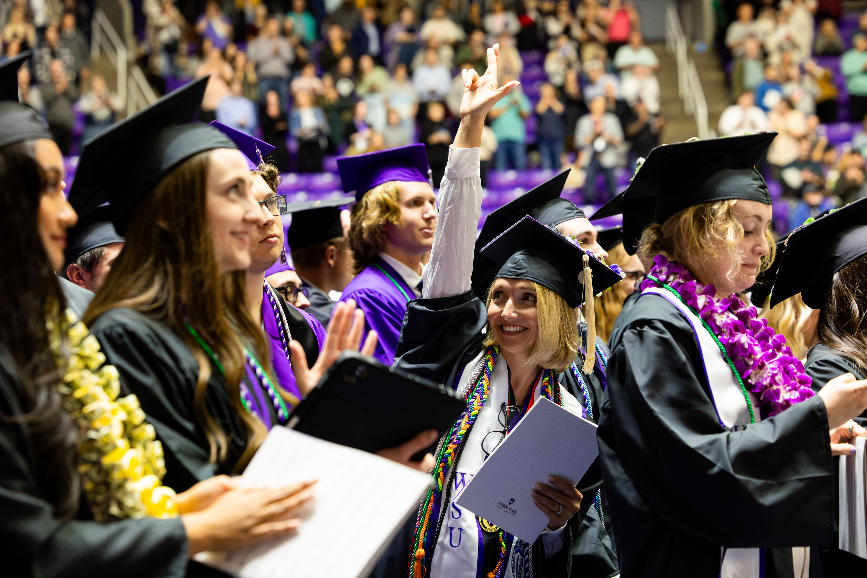 Graduates wave at members of the audience at Weber State University’s commencement program at the Dee Events Center in Ogden on Friday.