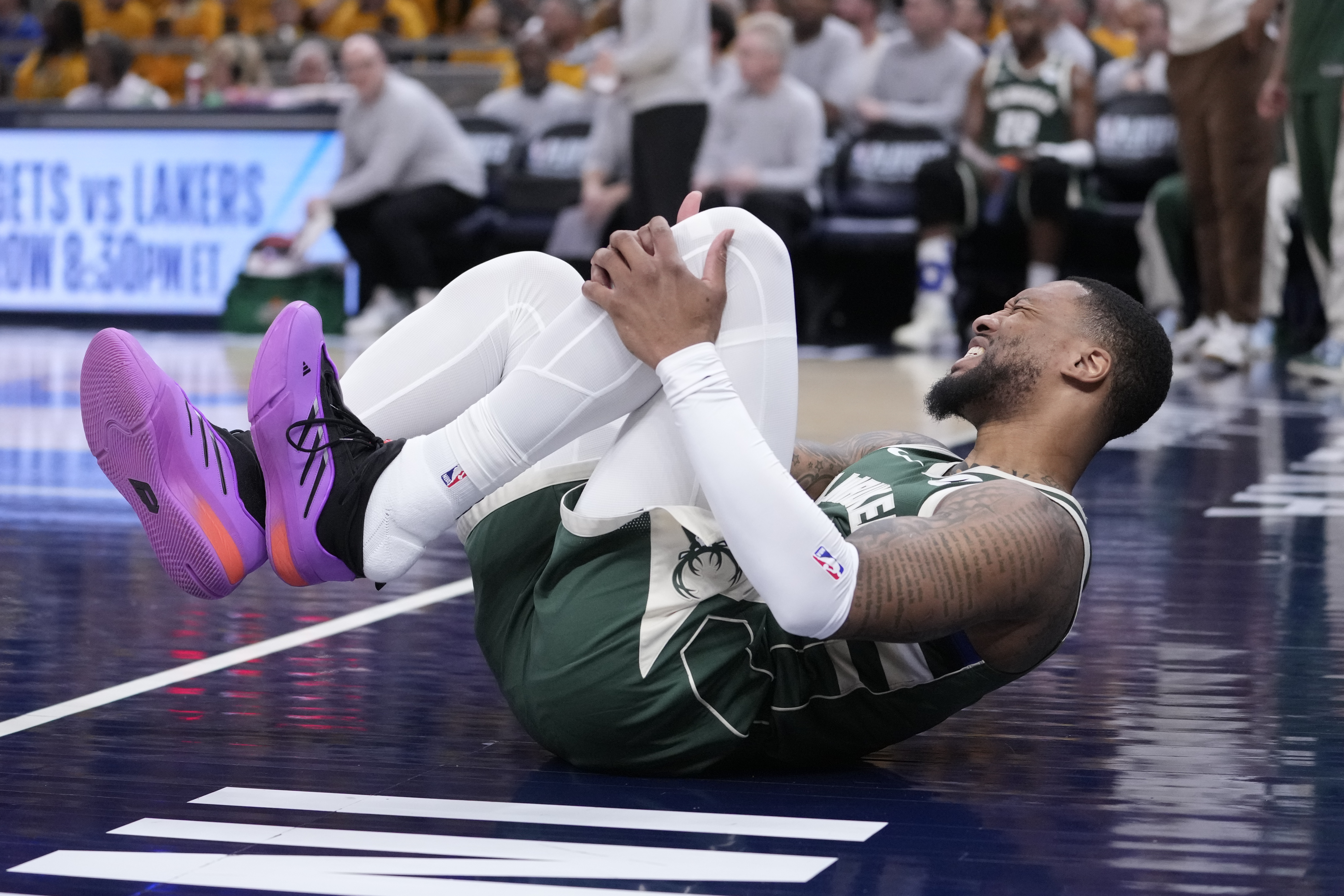 Milwaukee Bucks guard Damian Lillard (0) grabs his leg after being injured during the first half in Game 2 against the Indiana Pacers in an NBA basketball first-round playoff series, Friday, April 26, 2024, in Indianapolis.