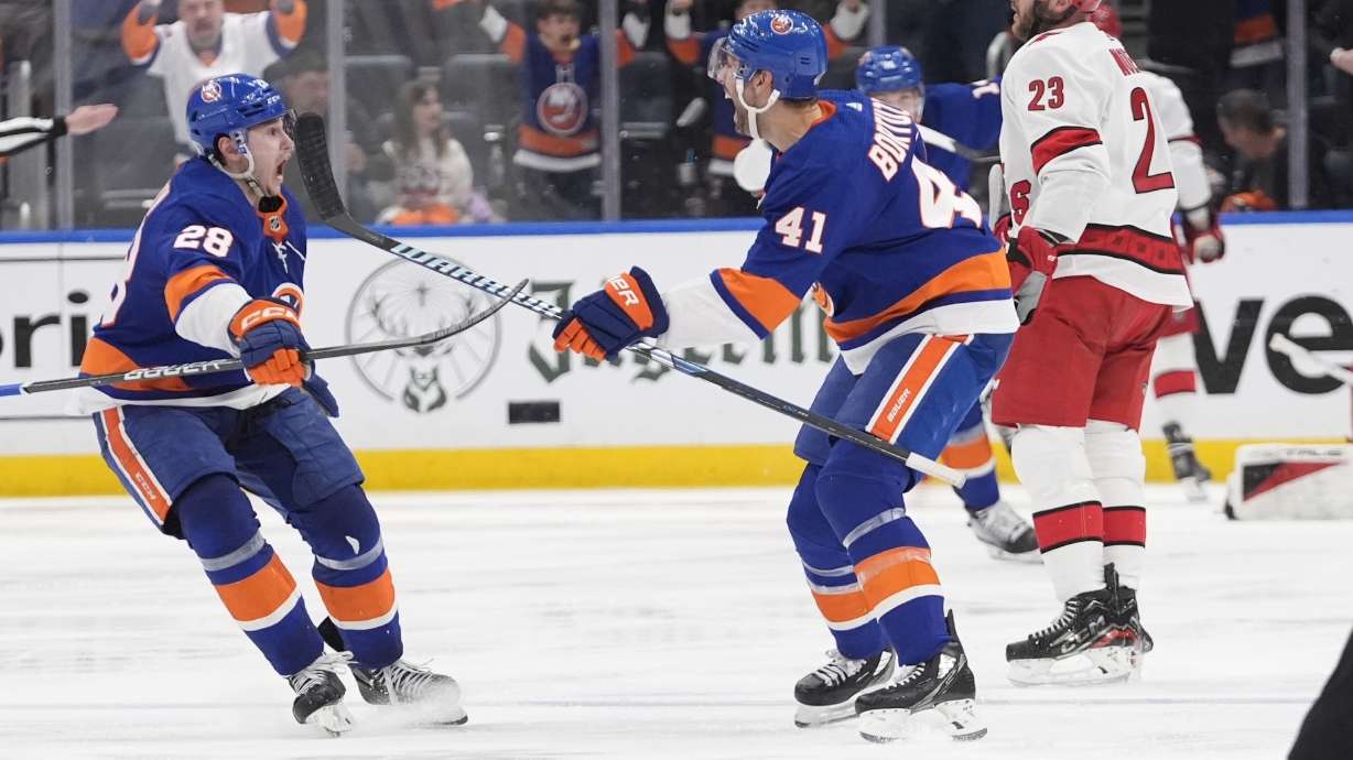 CORRECTS GOAL SCORER TO MATHEW BARZAL, NOT BORTUZZO - New York Islanders' Alexander Romanov (28) celebrates with Robert Bortuzzo (41) after Mathew Barzal scored the game-winning goal during the second overtime period of Game 4 of an NHL hockey Stanley Cup first-round playoff series against the Carolina Hurricanes, Saturday, April 27, 2024, in Elmont, N.Y.