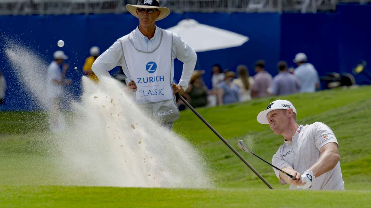 Patrick Fishburn, right, hits from a bunker on the 18th hole during the third round of the PGA Zurich Classic golf tournament at TPC Louisiana in Avondale, La., Saturday, April 27, 2024.