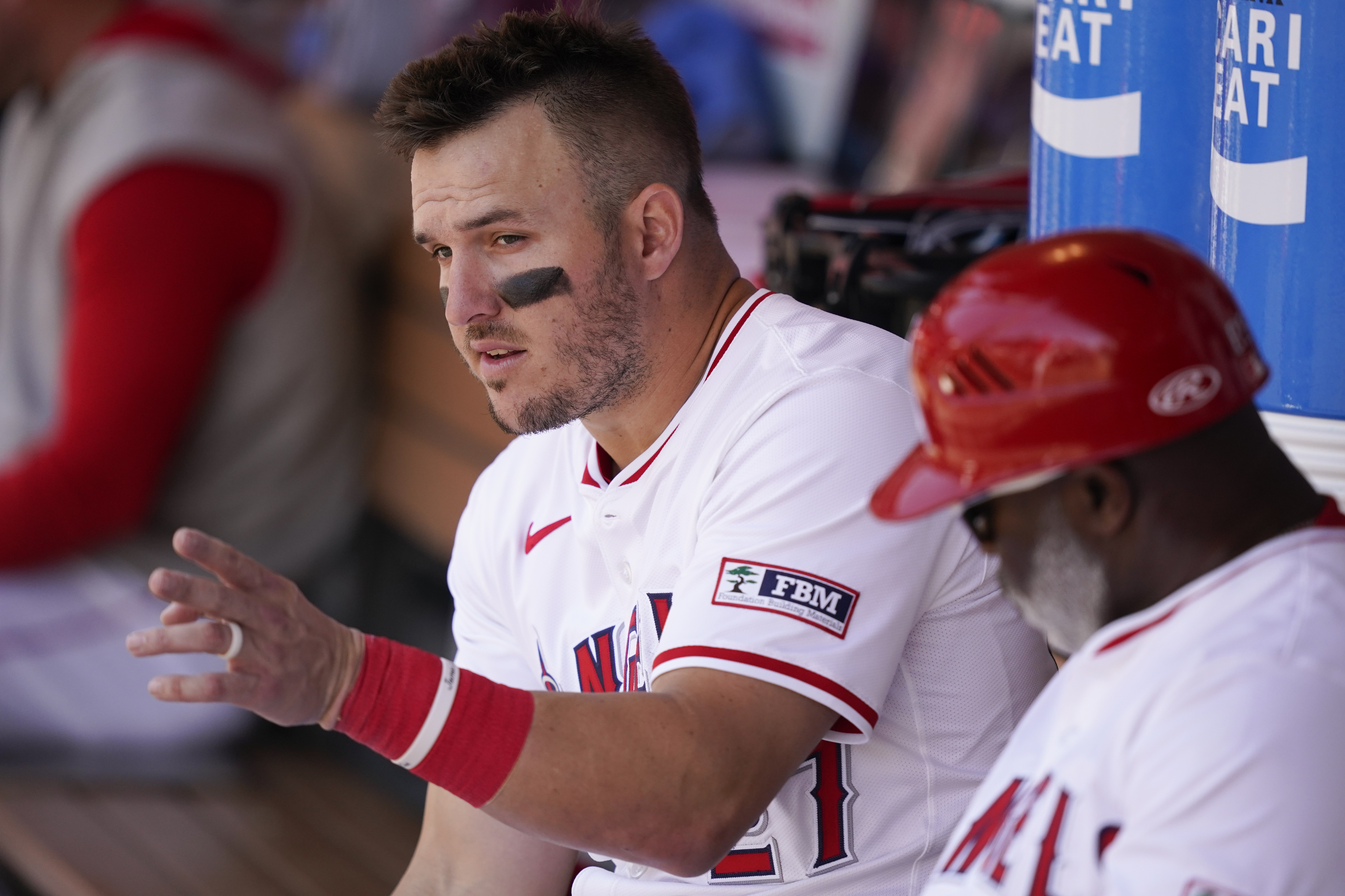 Los Angeles Angels designated hitter Mike Trout, left, speaks with third base coach Eric Young Sr. during the fifth inning of a baseball game against the Minnesota Twins, Sunday, April 28, 2024, in Anaheim, Calif.