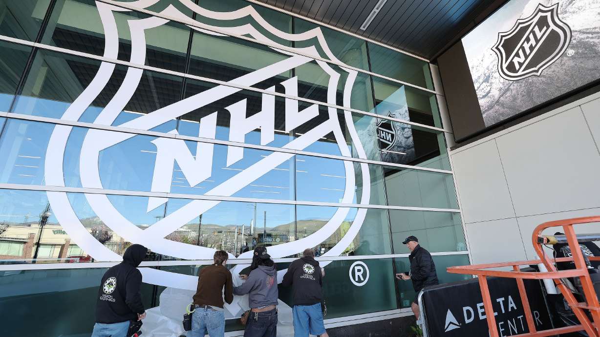 Vision Graphics crews install an NHL banner on the Delta Center in Salt Lake City on April 18. Jazz owner Ryan Smith bought the Arizona Coyotes, and they will relocate to Salt Lake City.