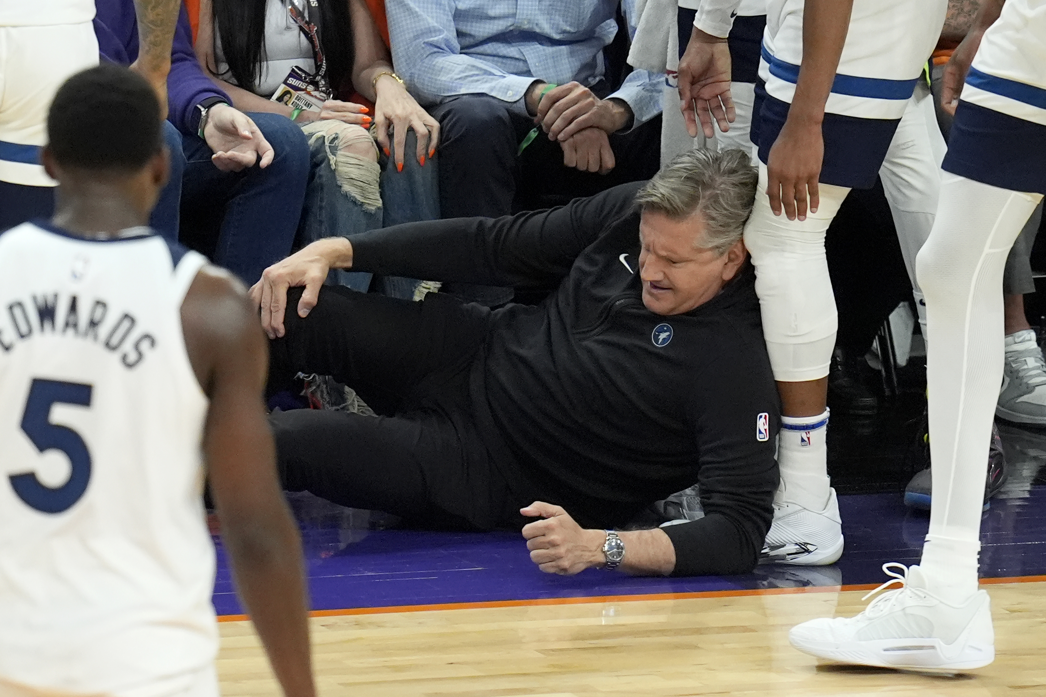 Minnesota Timberwolves head coach Chris Finch holds his knee after colliding with Timberwolves guard Mike Conley during the second half of Game 4 of an NBA basketball first-round playoff series against the Phoenix Suns Sunday, April 28, 2024, in Phoenix. The Timberwolves won 122-116, taking the series 4-0.