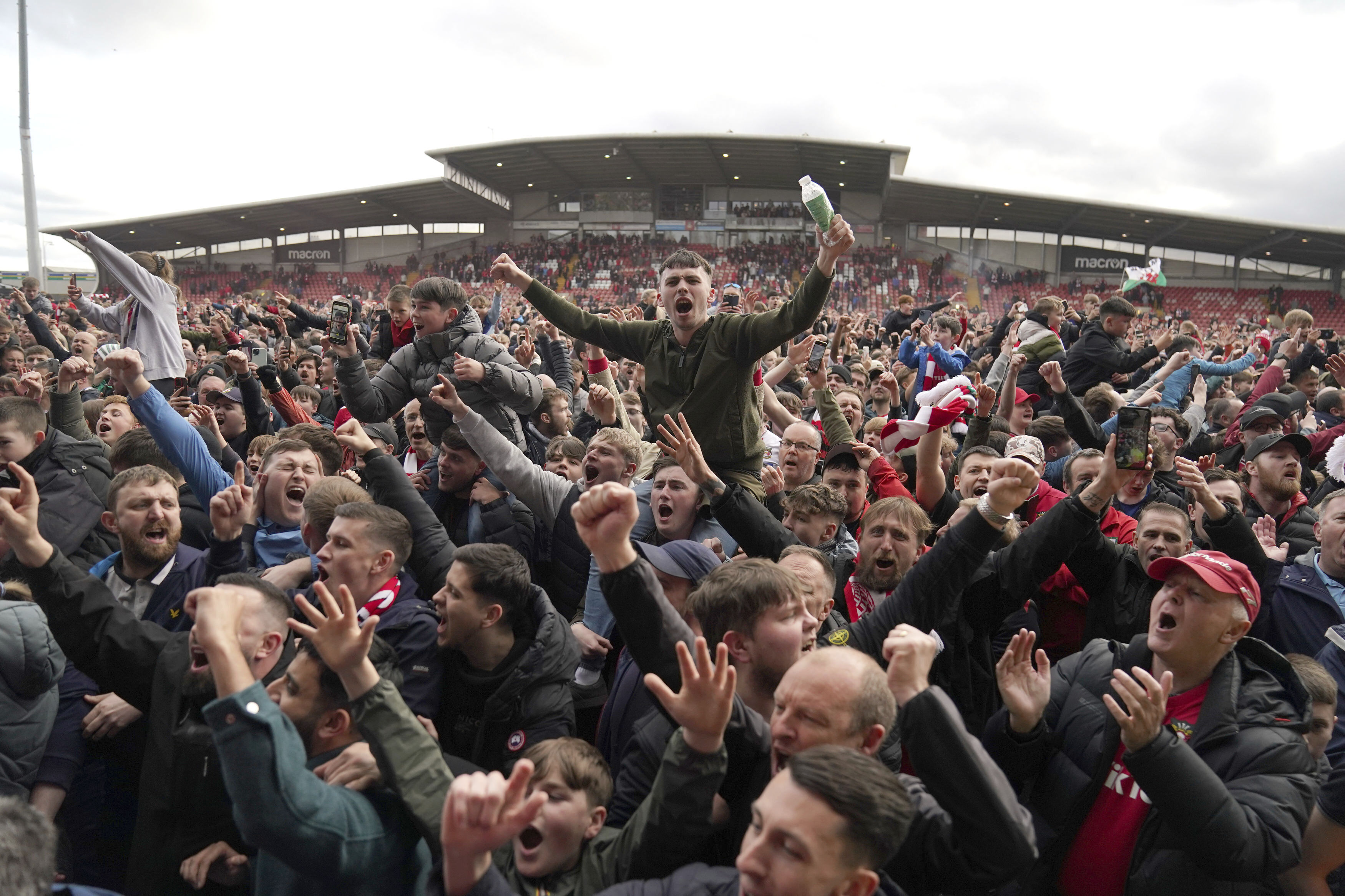Wrexham fans invade the pitch celebrating promotion to League One after the final whistle of a League Two soccer match, Saturday, April 13, 2024, in Wrexham, Wales. The Welsh team co-owned by actor Ryan Reynolds clinched promotion to the third tier of English soccer thanks to a 6-0 home win over Forest Green on Saturday. 