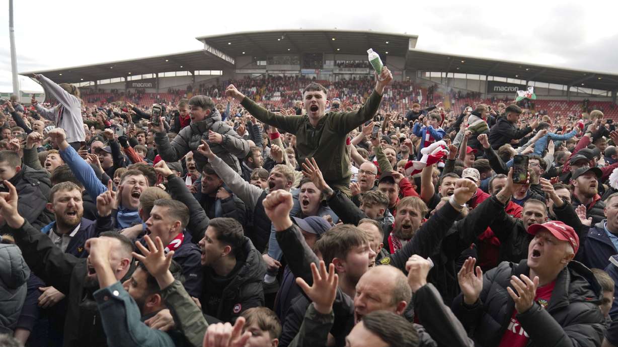 Wrexham fans invade the pitch celebrating promotion to League One after the final whistle of a League Two soccer match, Saturday, April 13, 2024, in Wrexham, Wales. The Welsh team co-owned by actor Ryan Reynolds clinched promotion to the third tier of English soccer thanks to a 6-0 home win over Forest Green on Saturday.