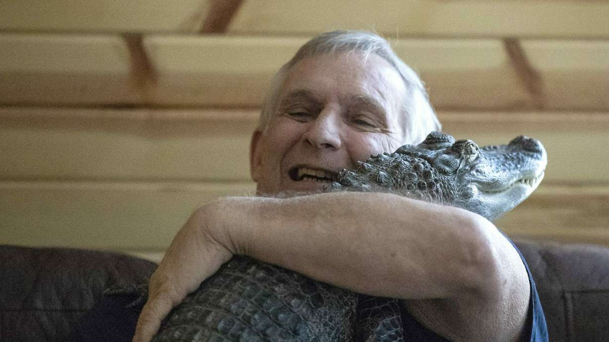 Joie Henney hugs his emotional support alligator named Wally, Jan. 22, 2019, inside their home in York Haven, Pa. Wally has gone missing amid the coastal marshes of Georgia.