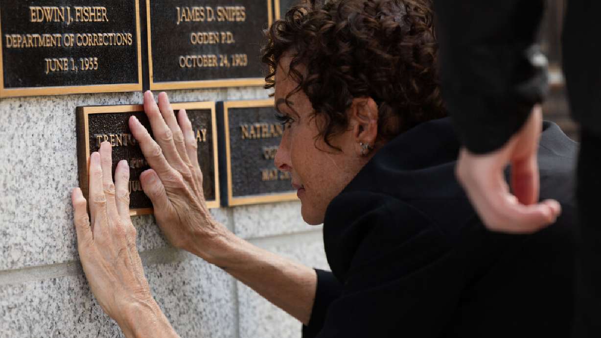 Lisa Halladay, wife of officer Trenton F. Halladay, places a plaque with his name on the memorial wall during a memorial service at the Utah Law Enforcement Memorial outside of the state Capitol in Salt Lake City on Thursday.