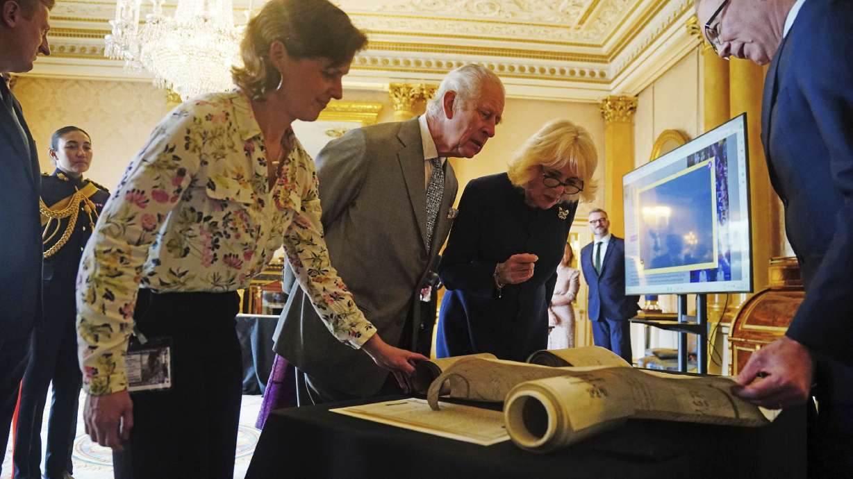 Britain's King Charles III and Queen Camilla are shown Coronation Rolls of previous monarchs after being presented with their own Coronation Roll, an official record of their Coronation, at Buckingham Palace, central London, Wednesday.