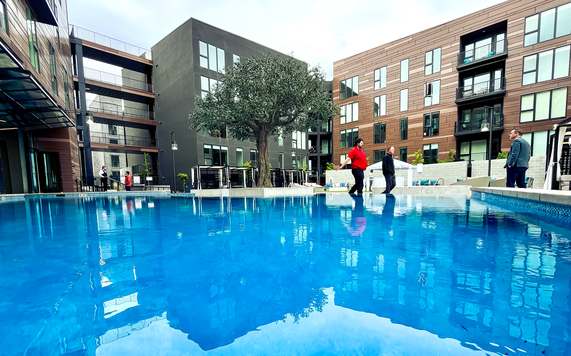 People tour an outdoor patio and pool area between Post District apartment complexes on May 2, 2024. The large mixed-use project is now completed, with over 500 units and multiple business spaces.