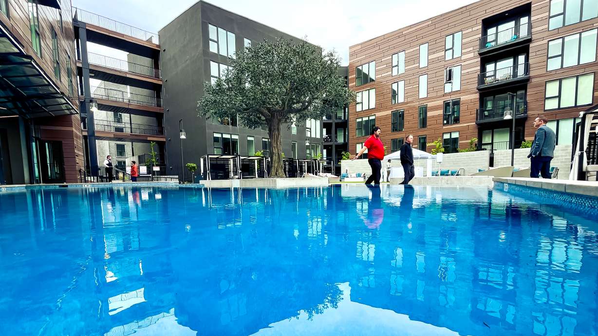 People tour an outdoor patio and pool area between Post District apartment complexes on Thursday. The large mixed-use project is now completed, with over 500 units and multiple business spaces.