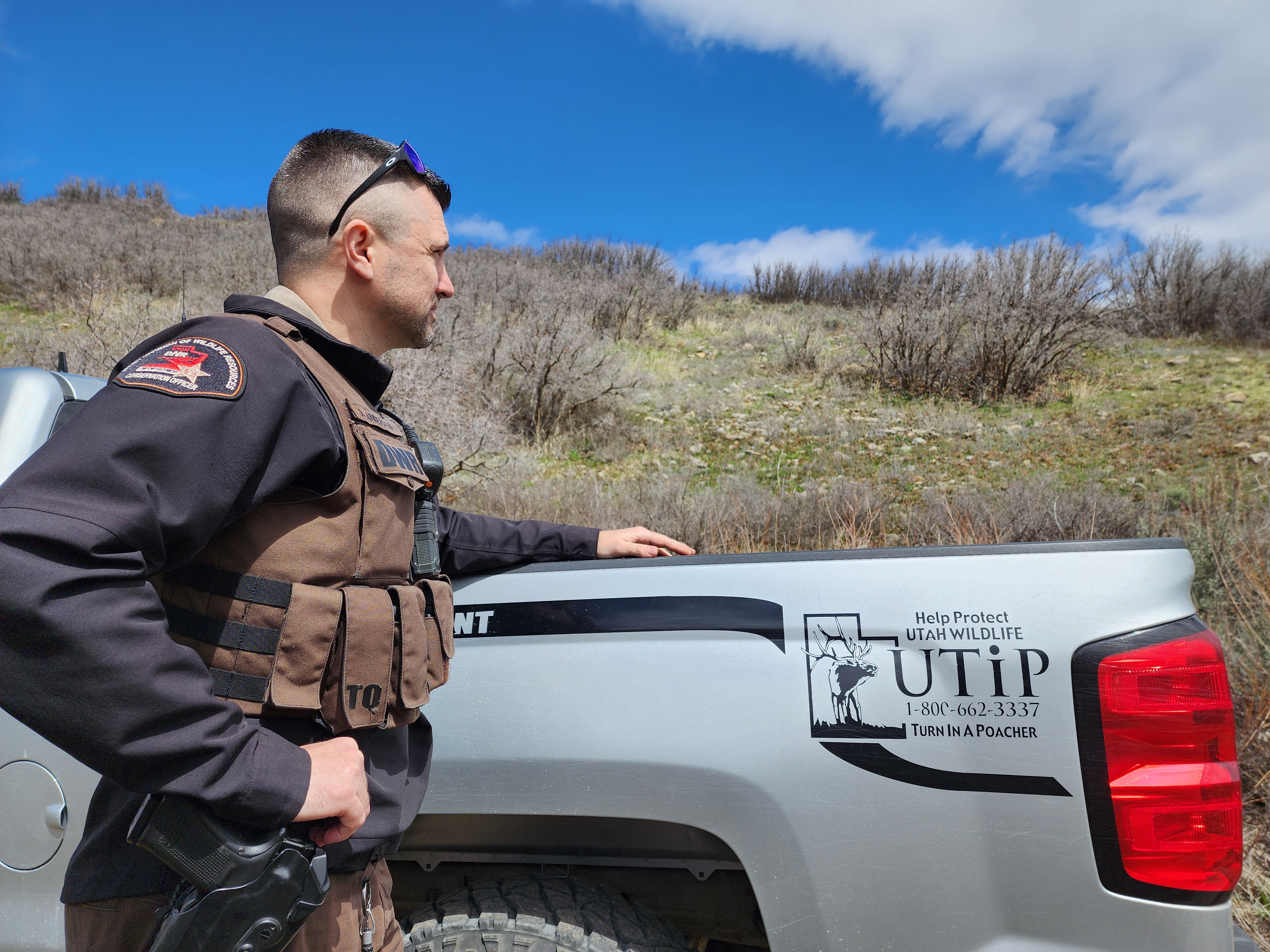 Utah wildlife conservation officer Jason Anderson stands at the scene of a poaching case in Salt Lake County that has been successfully prosecuted. The public tip line is shown on his truck.