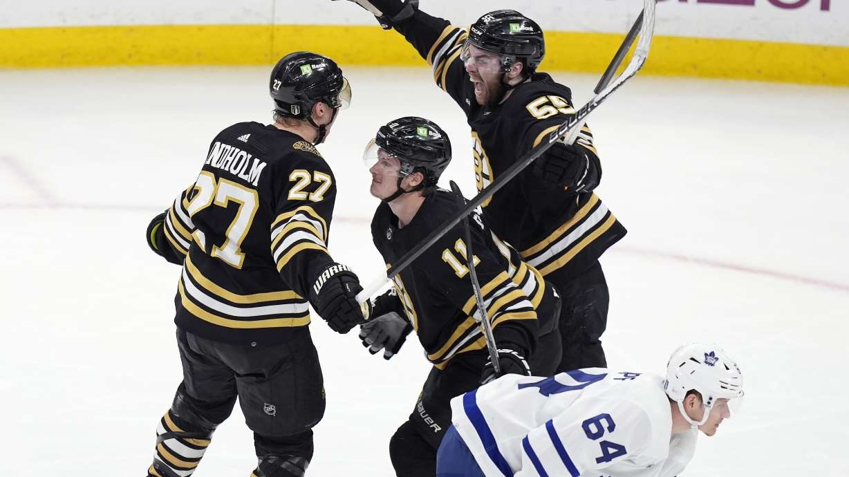 Boston Bruins' Hampus Lindholm (27) celebrates his goal with Justin Brazeau (55) and Trent Frederic (11) behind Toronto Maple Leafs' David Kampf (64) during the third period of Game 7 of an NHL hockey Stanley Cup first-round playoff series, Saturday, May 4, 2024, in Boston.