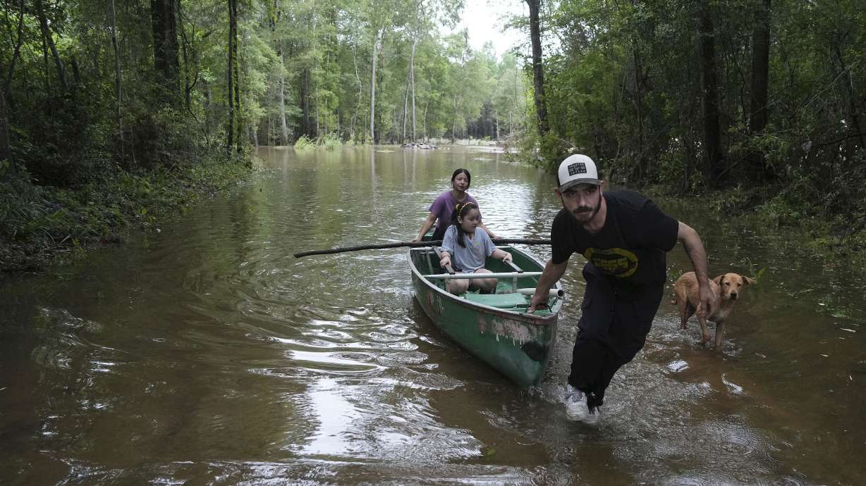 Alvaro Trevino pulls a canoe with Jennifer Tellez and Ailyn, 8, after they checked on their home on Sunday in Spendora, Texas. Floodwaters closed some Texas schools after days of heavy rains.