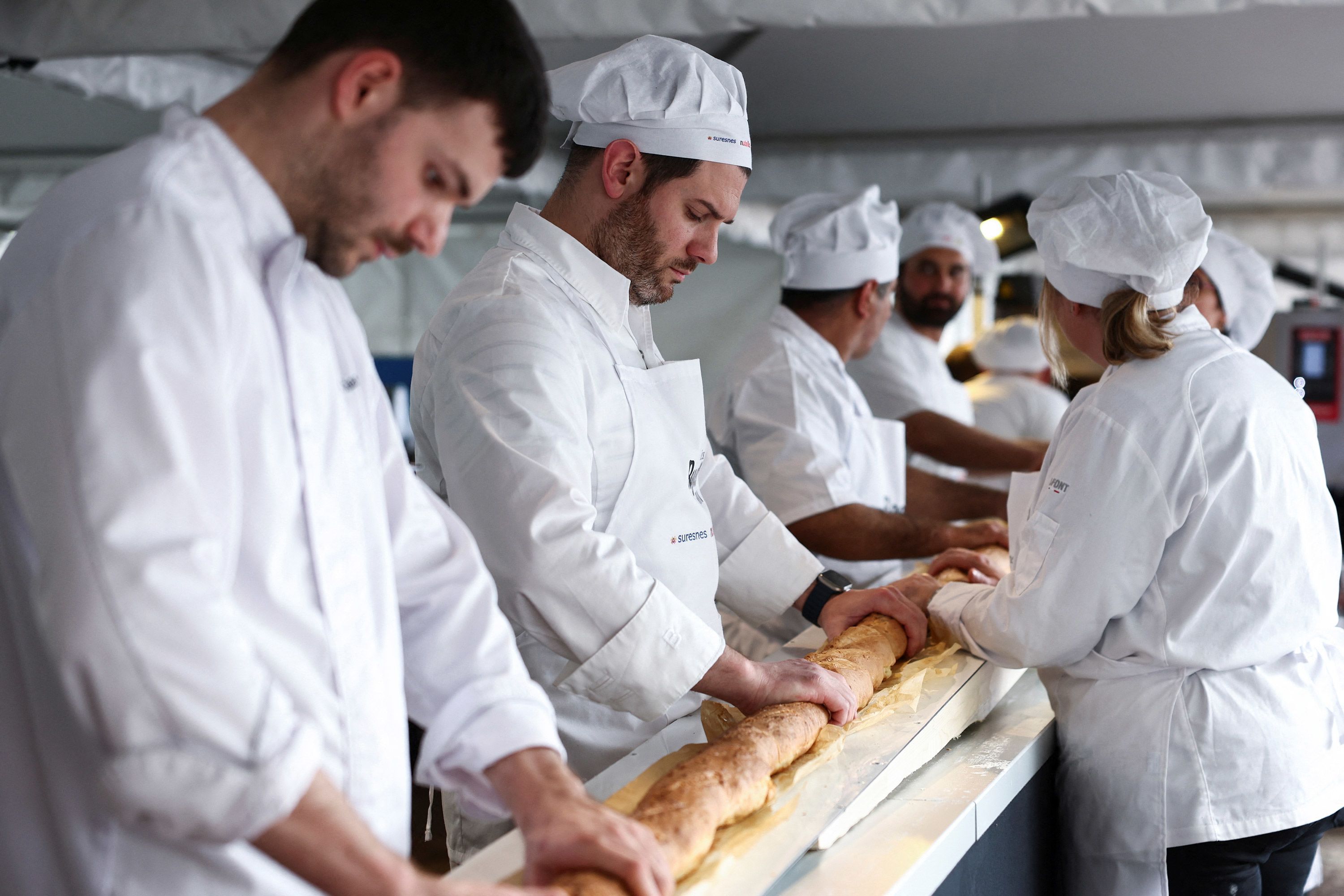 French bakers try not to crack the baguette when it comes out of a large rotating oven. French bakers have taken the record for the longest baguette ever made.