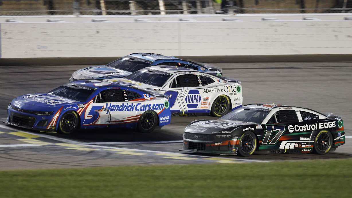 Kyle Larson (5) crosses the finish line milliseconds in front of Chris Buescher (17) for the win during a NASCAR Cup Series auto race at Kansas Speedway in Kansas City, Kan., Sunday, May 5, 2024.