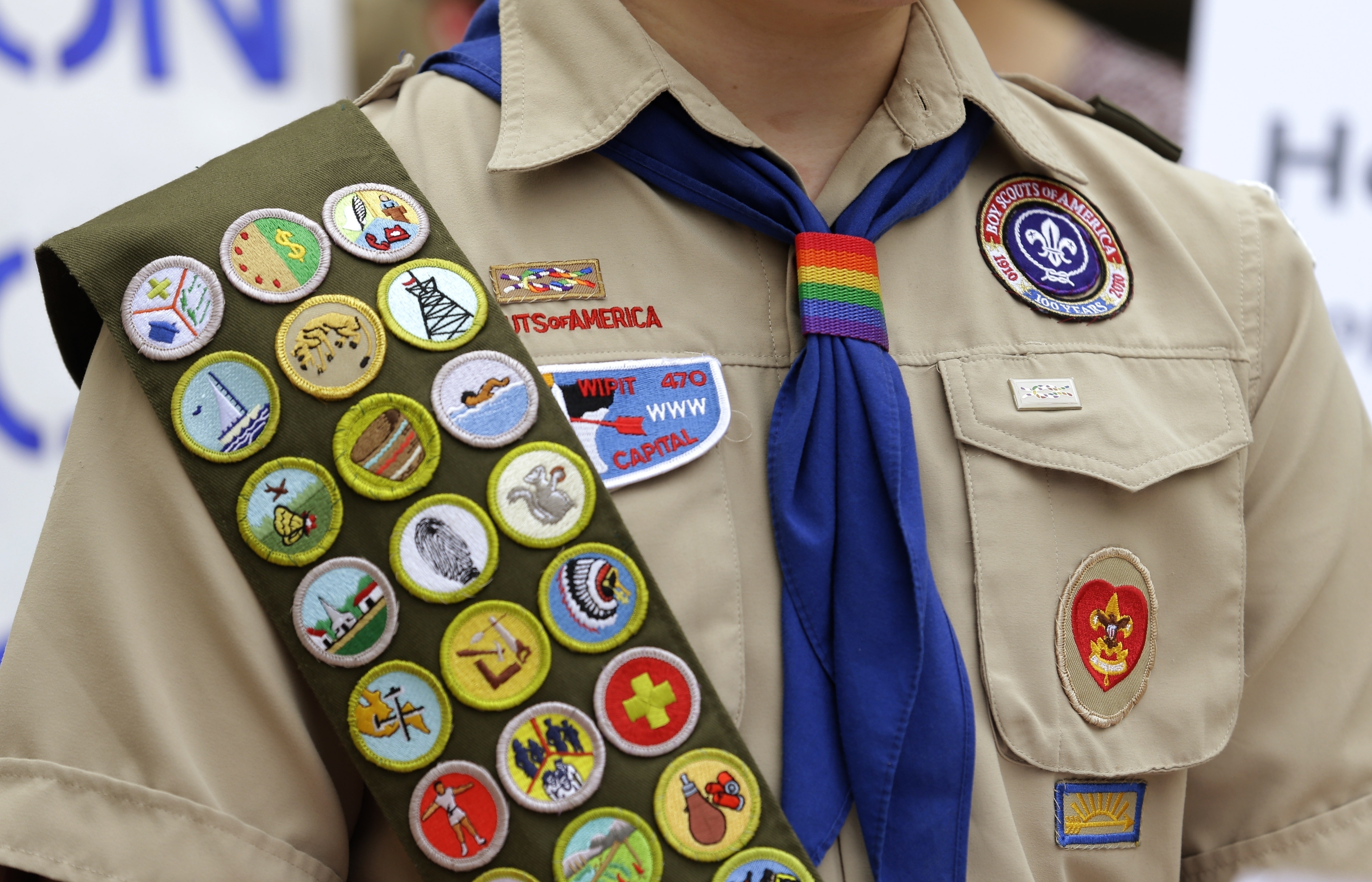Merit badges and a rainbow-colored neckerchief slider are affixed on a Boy Scout uniform outside the headquarters of Amazon in Seattle. The U.S. organization, which now welcomes girls into the program and allows them to work toward the coveted Eagle Scout rank, announced Tuesday, that it will change its name to Scouting America as it focuses on inclusion.