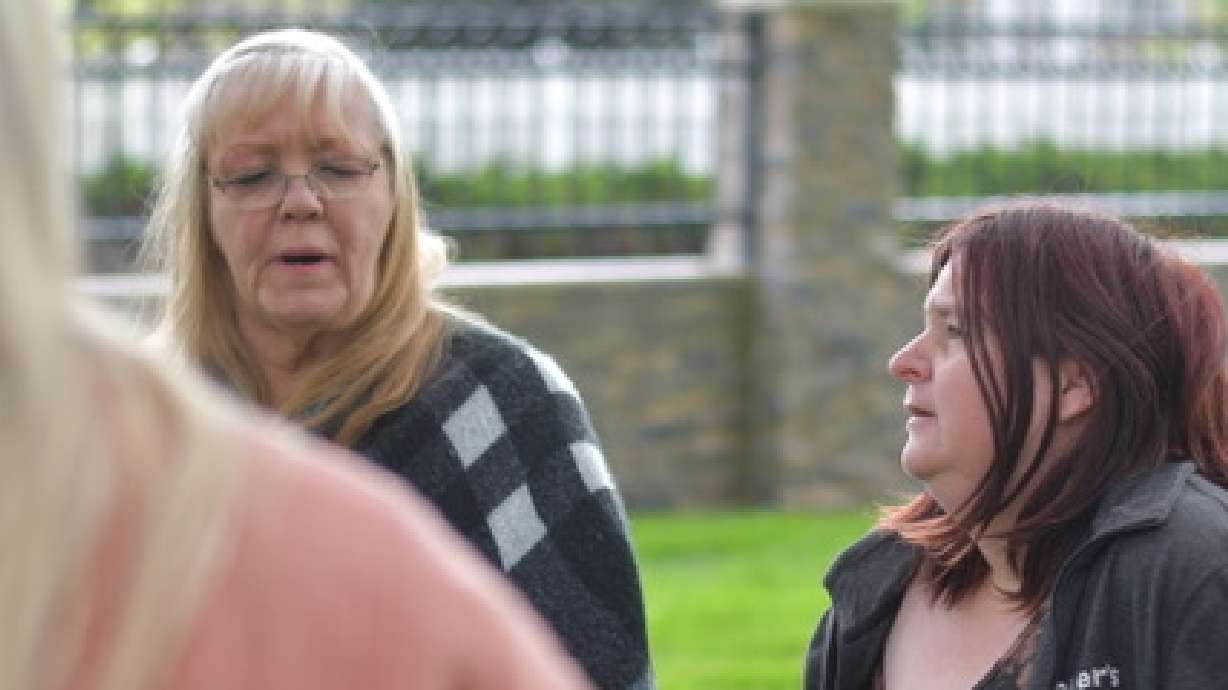 Carla Maas, left, and her daughter Dana Booth Christensen, talk at the grave of Buddy Booth in April in Salt Lake City. Booth was Maas' husband and Christensen's father.