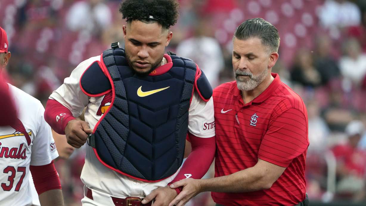 St. Louis Cardinals catcher Willson Contreras, left, is helped off the field by trainer Adam Olsen, right, after being injured during the second inning of a baseball game against the New York Mets Tuesday, May 7, 2024, in St. Louis. Contreras left the game.