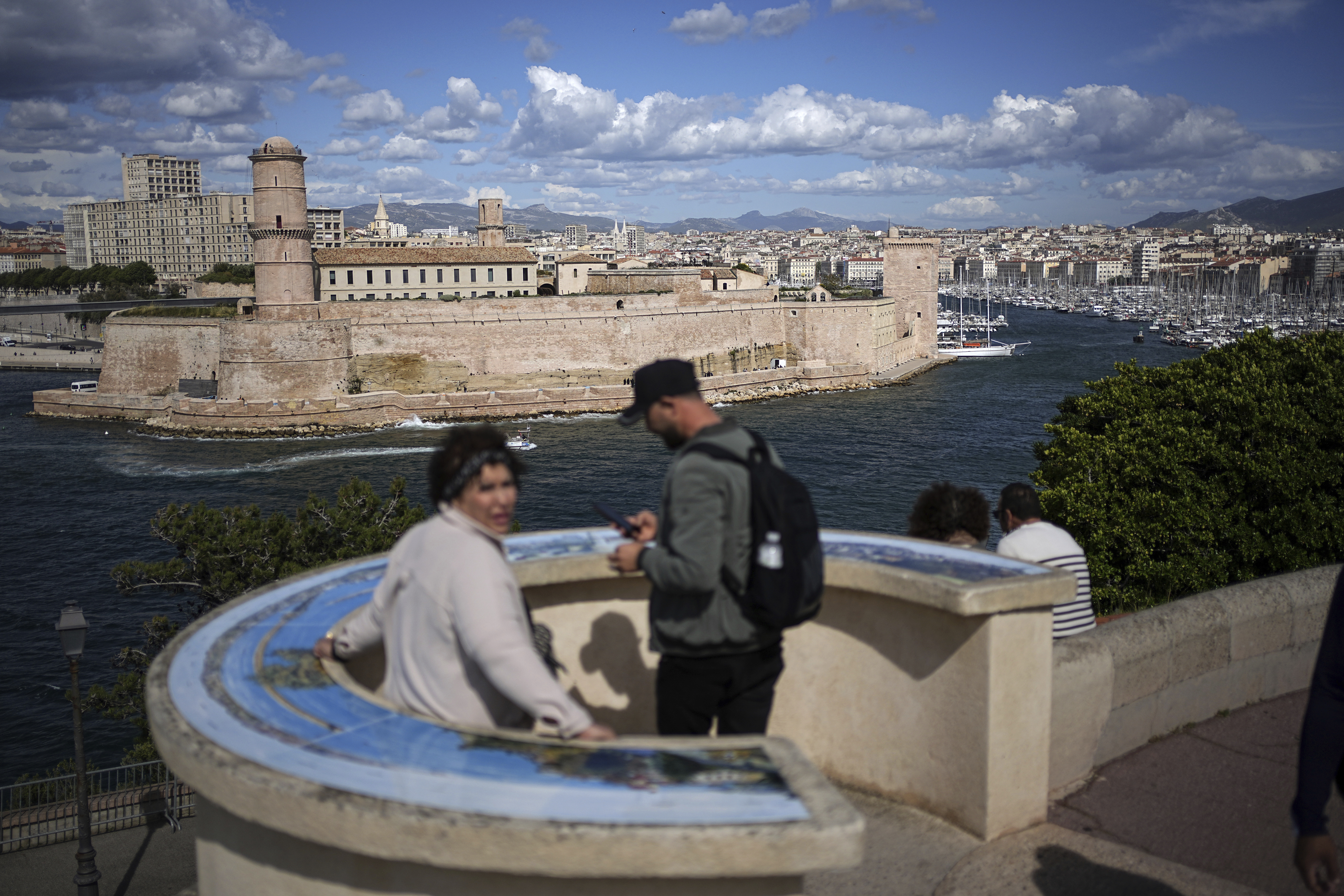 People stand in the gardens of the Palais du Pharo, overlooking the old port, the day ahead of the arrival of the Olympic flame, in Marseille, southern France, Tuesday, May 7, 2024. The Olympic torch will finally enter France when it reaches the southern seaport of Marseille on Wednesday.