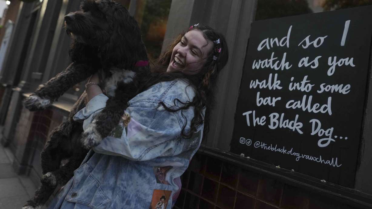 Taylor Swift fan Brodie MacArthur from east London poses next to a sign featuring Taylor Swift lyrics outside The Black Dog pub in London, May 4. U.S. fans are following Swift to Europe.